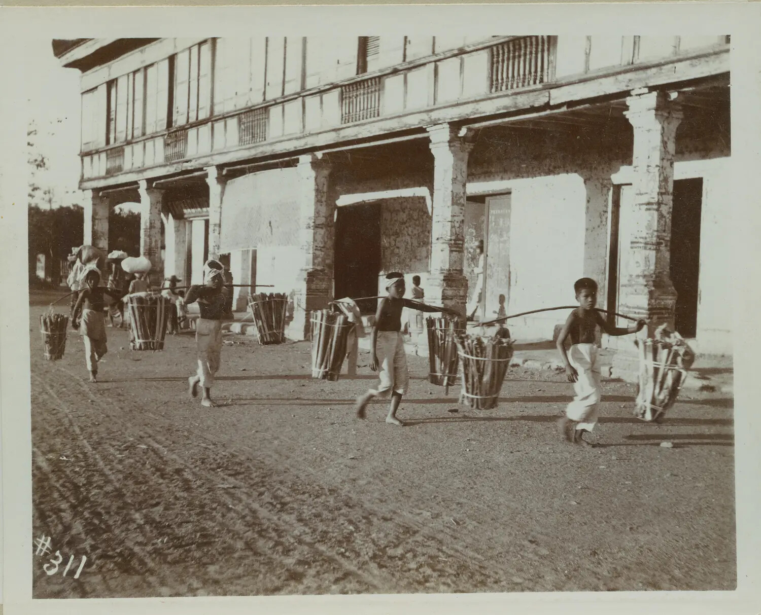 Filipino Porters Carrying Baskets on Shoulder Poles, Philippines, c. 1890s-1900s