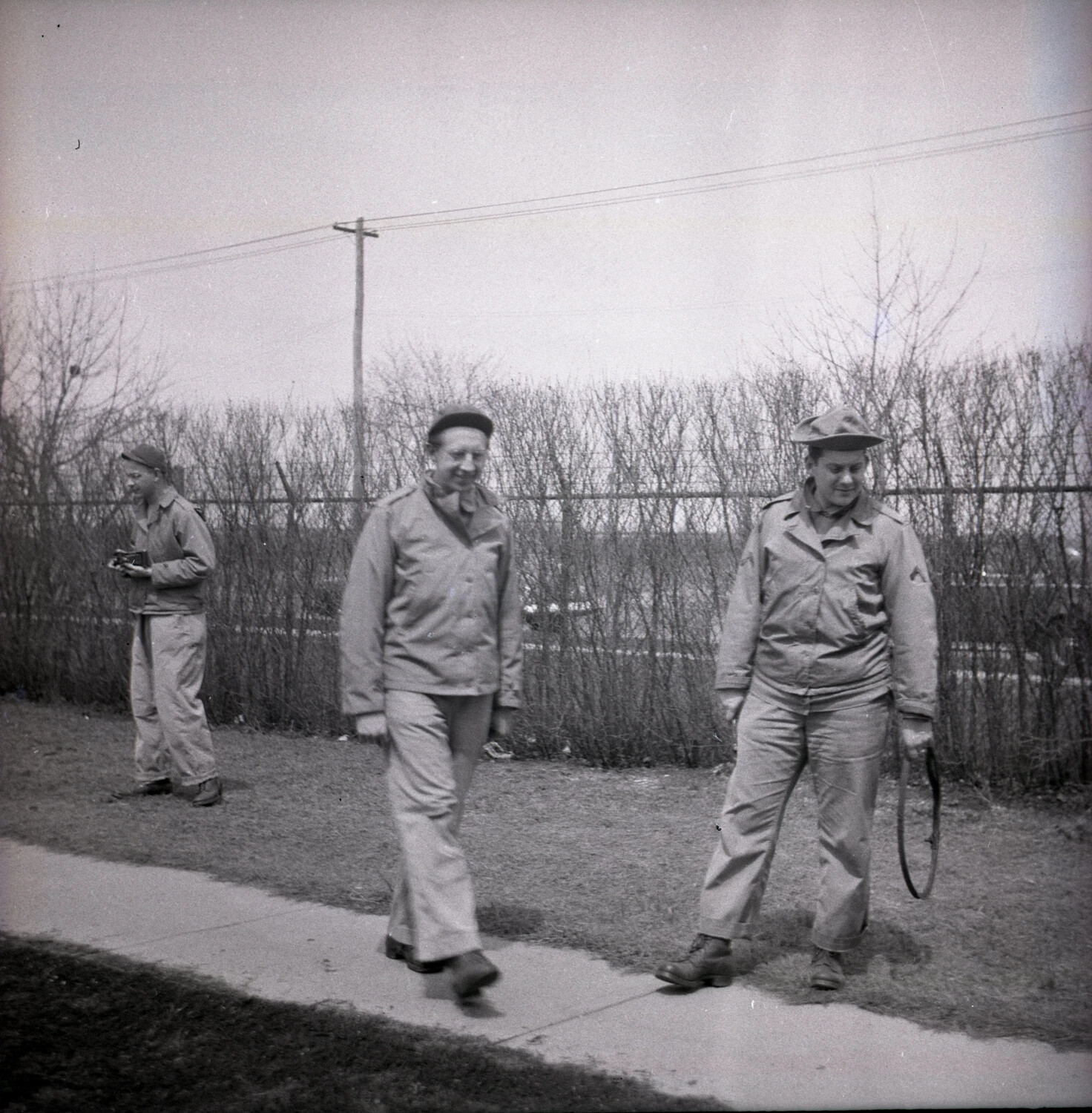 Servicemen Walking Along Perimeter Fence Line, Base Grounds