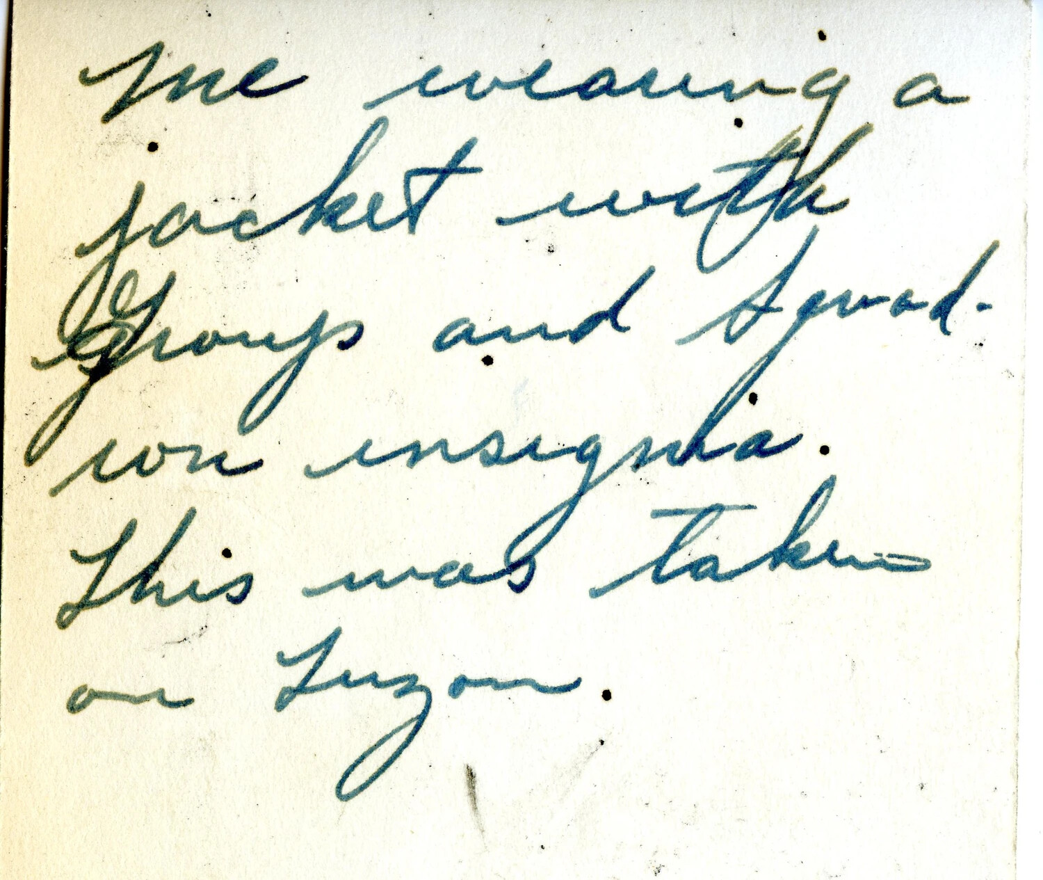 Handwritten Album Caption Card: 'Wearing a Jacket with Group and Squadron Insignia – Taken on Luzon'