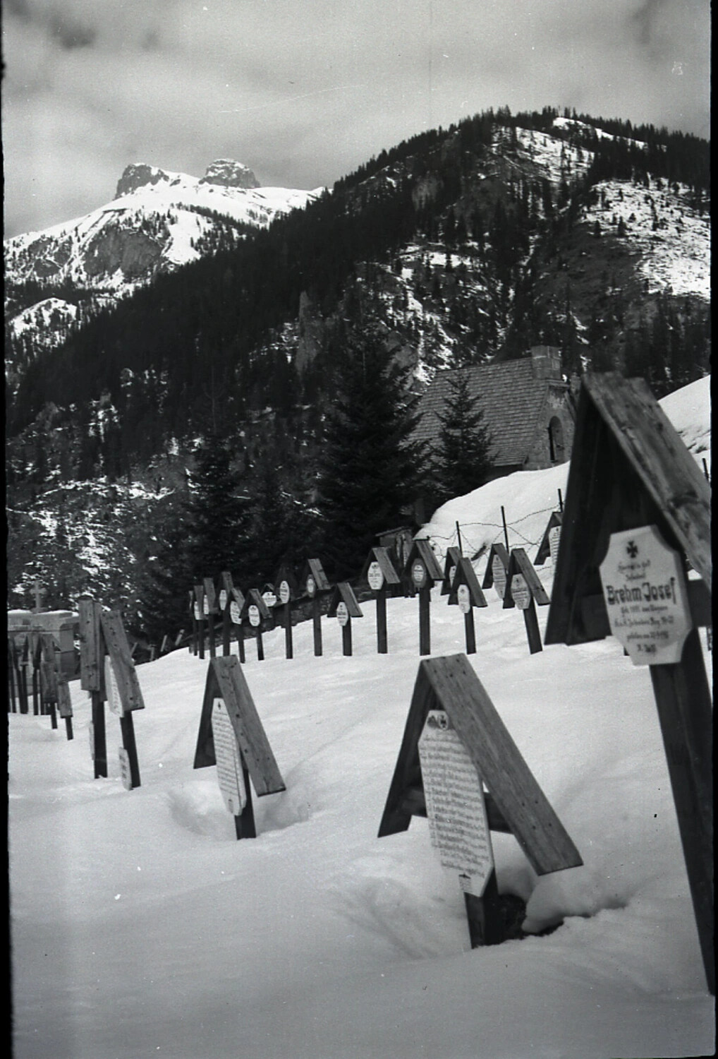 Snow-Covered Alpine Military Cemetery with Wooden Grave Markers and Iron Cross Emblems