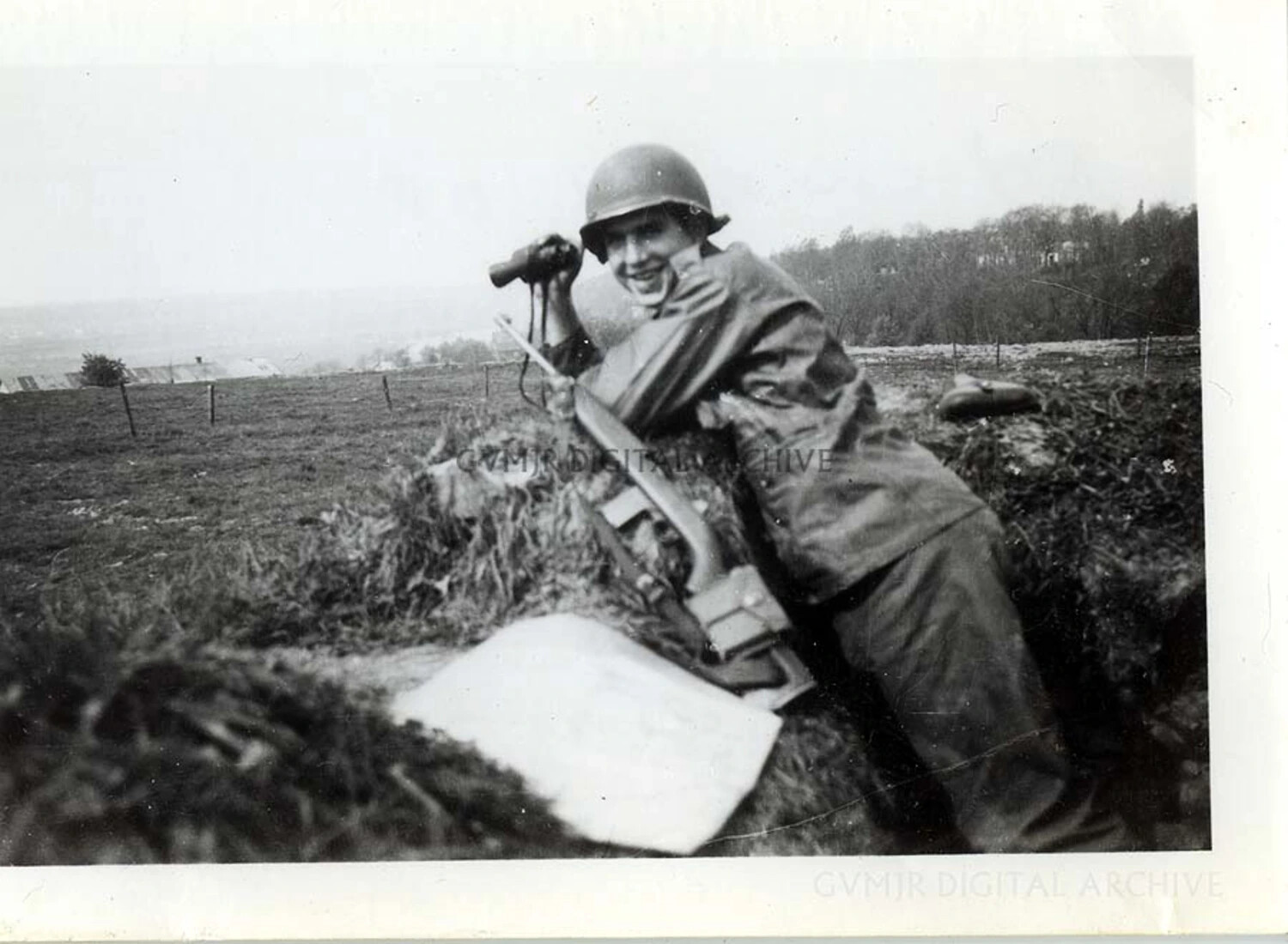 Smiling Paratrooper with Binoculars, Weapon, and Ground Identification Panel in a Foxhole, WWII