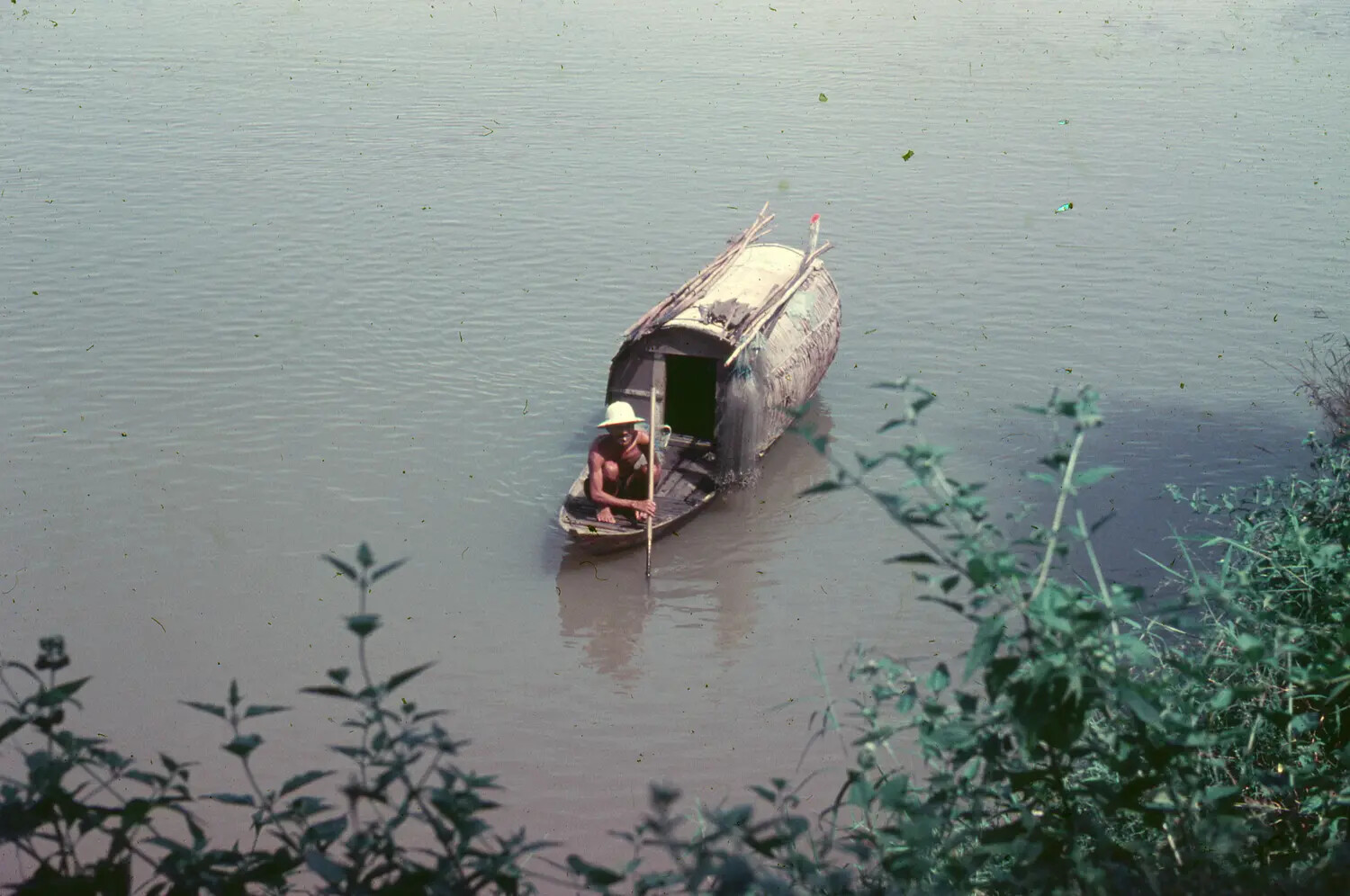 Vietnamese Boatman Poling a Covered Sampan on a River, Vietnam, 1965