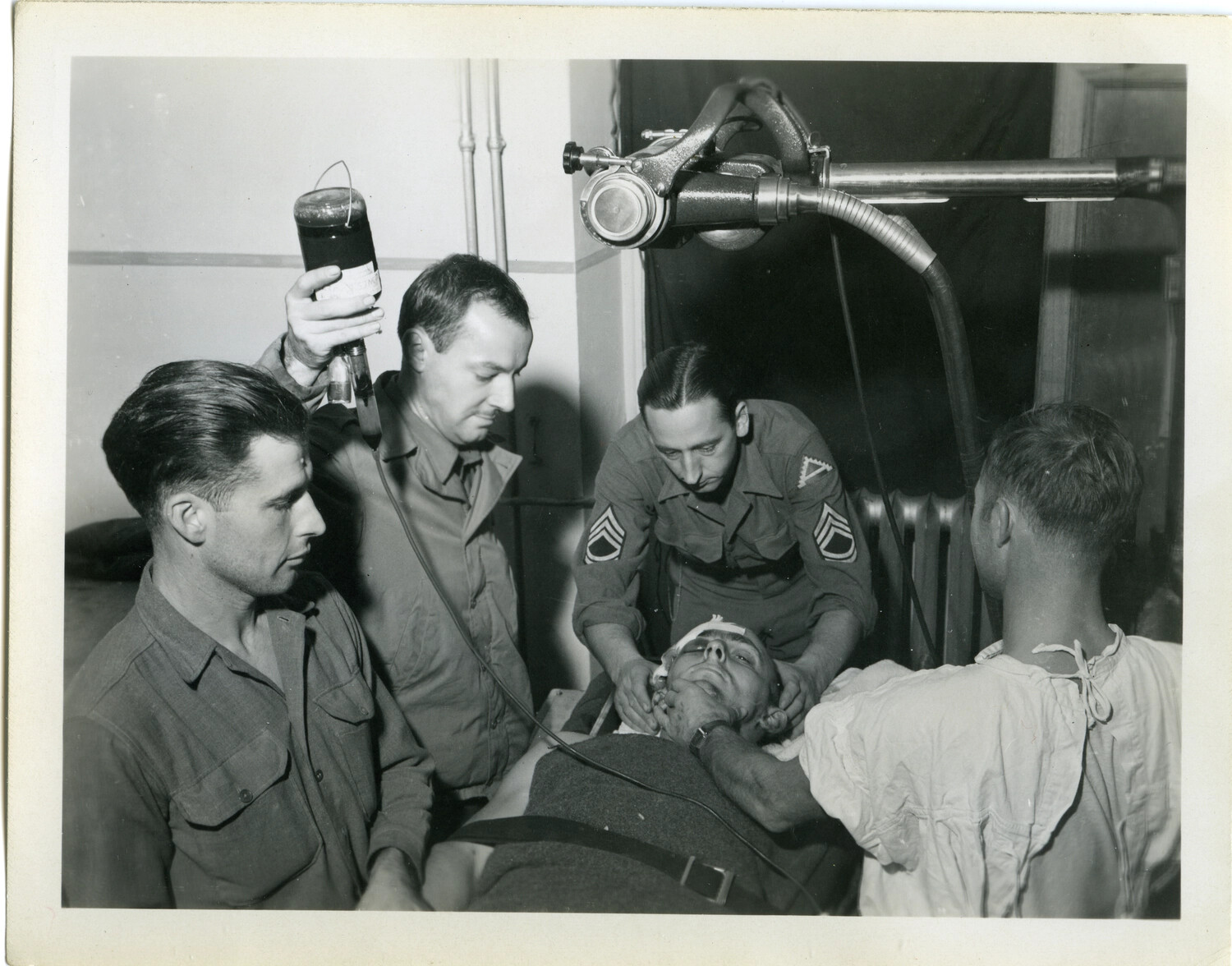 Field Hospital Personnel Administering Plasma Transfusion to Wounded Soldier