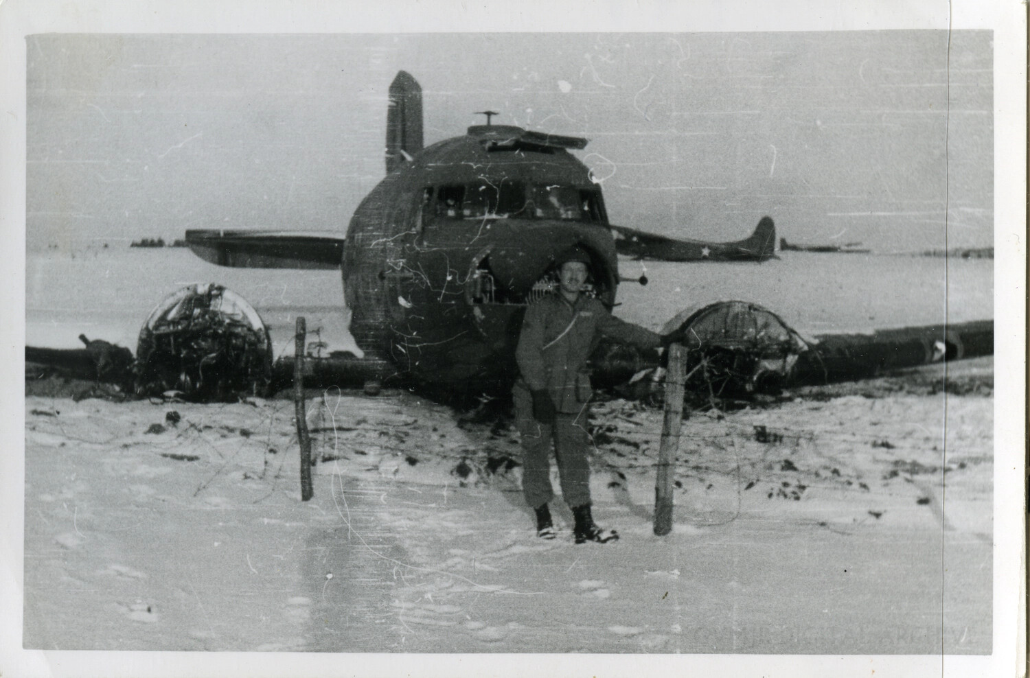 U.S. Soldier Posing Beside Wrecked Twin-Engine Aircraft in Snow — Ardennes Campaign, Winter 1944-45
