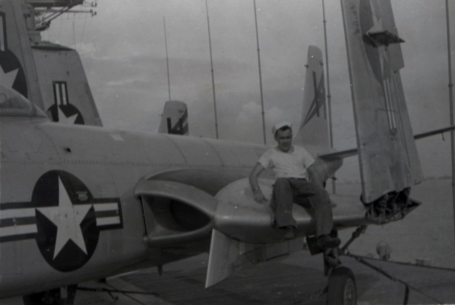 Sailor Seated on Folded Wing of F4U Corsair Fighter, USS Yorktown (CV-10), 1953