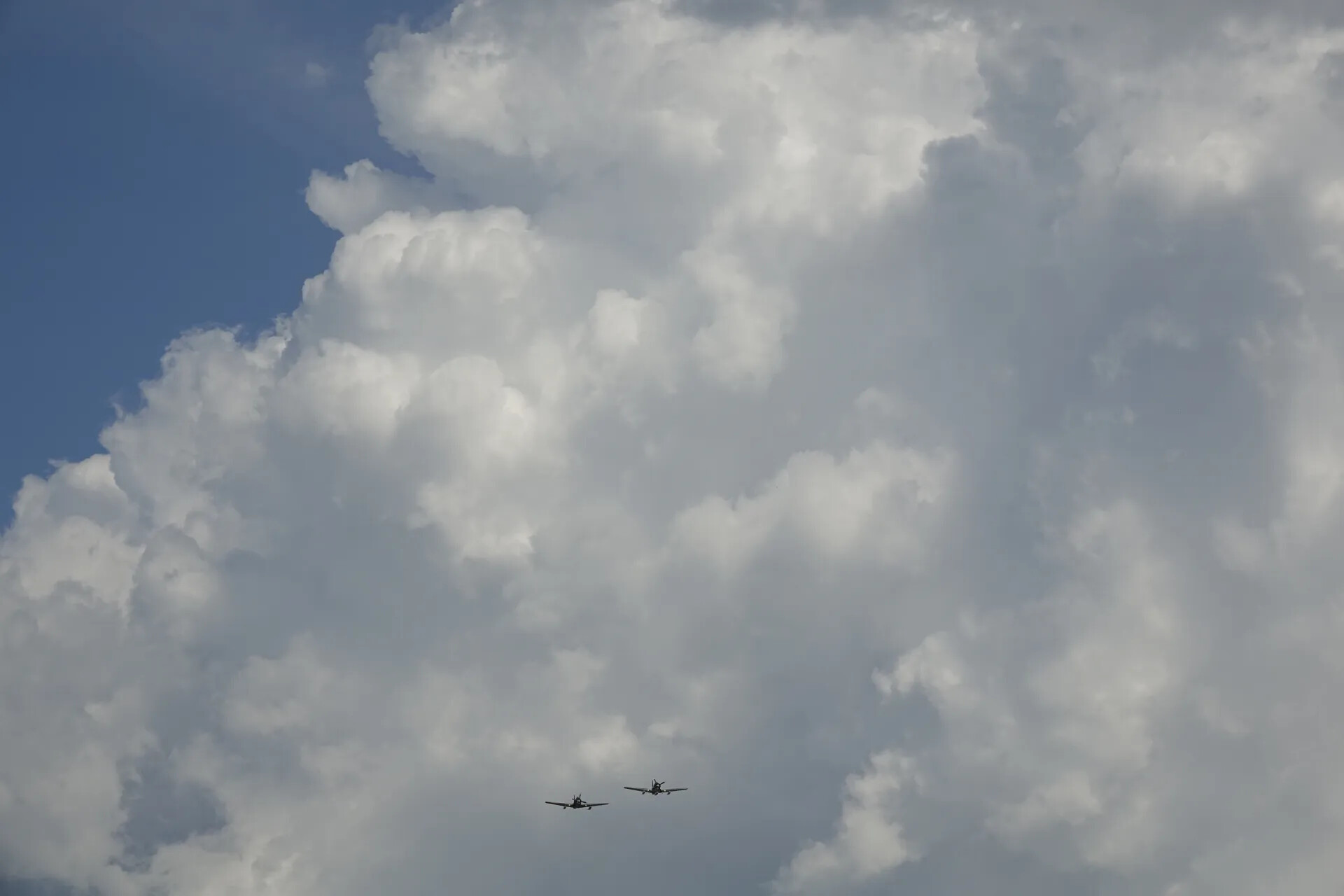 Formation Flight of Two A-1 Skyraider-Type Aircraft Against Cumulus Clouds