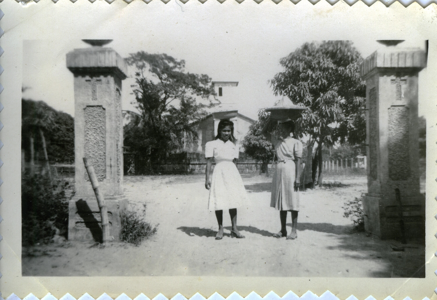 Two Women at a Cross-Topped Stone Gateway Near a Church, Pacific Theater, WWII Era