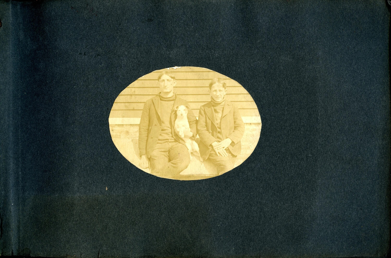 Two Young Men with Dog, Front Porch Portrait — Front Matter, USS Columbia Album (N. Fitchelberg), circa 1900-1910