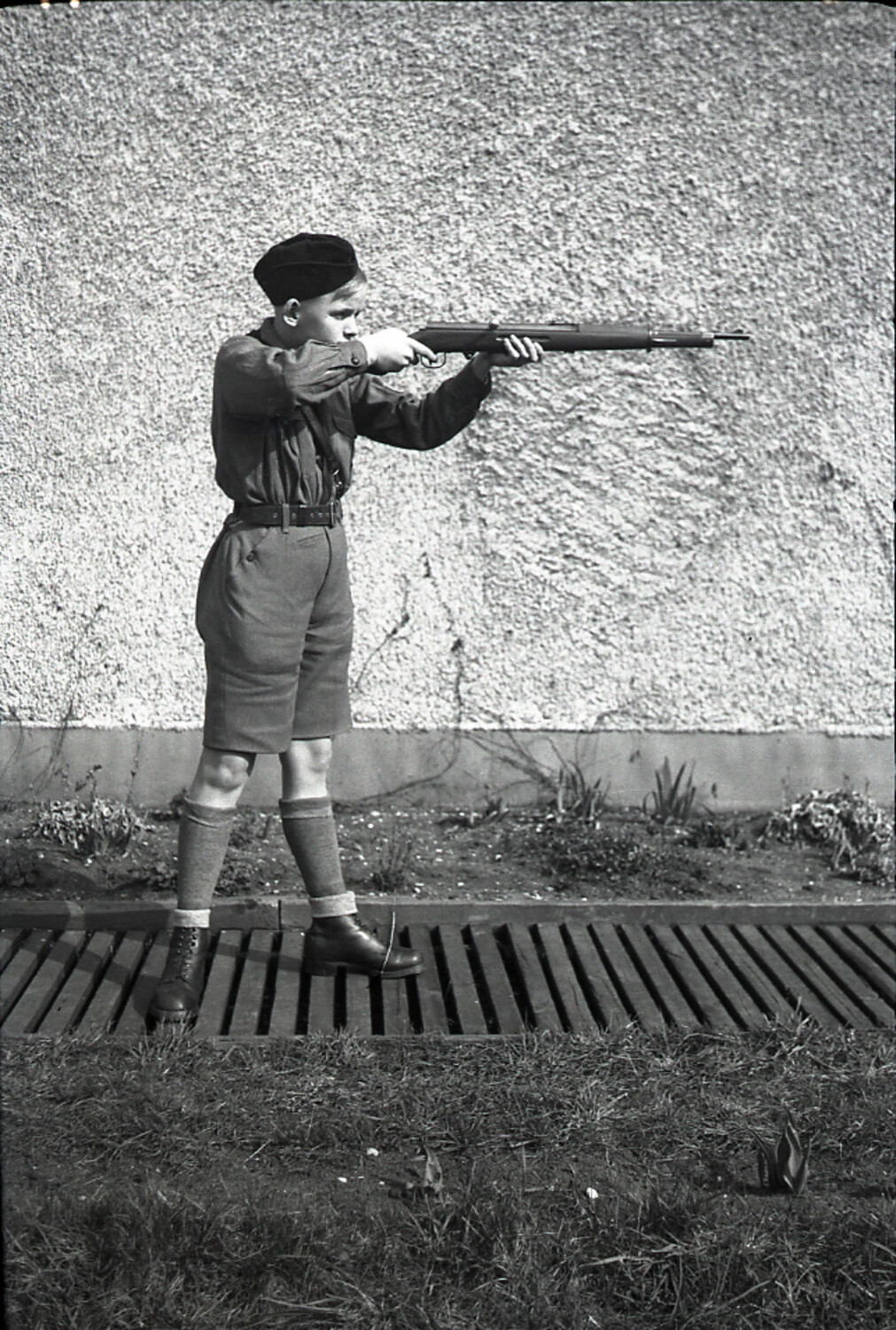 Youth in Shorts and Cap Aiming a Rifle One-Handed, Germany, WWII Era