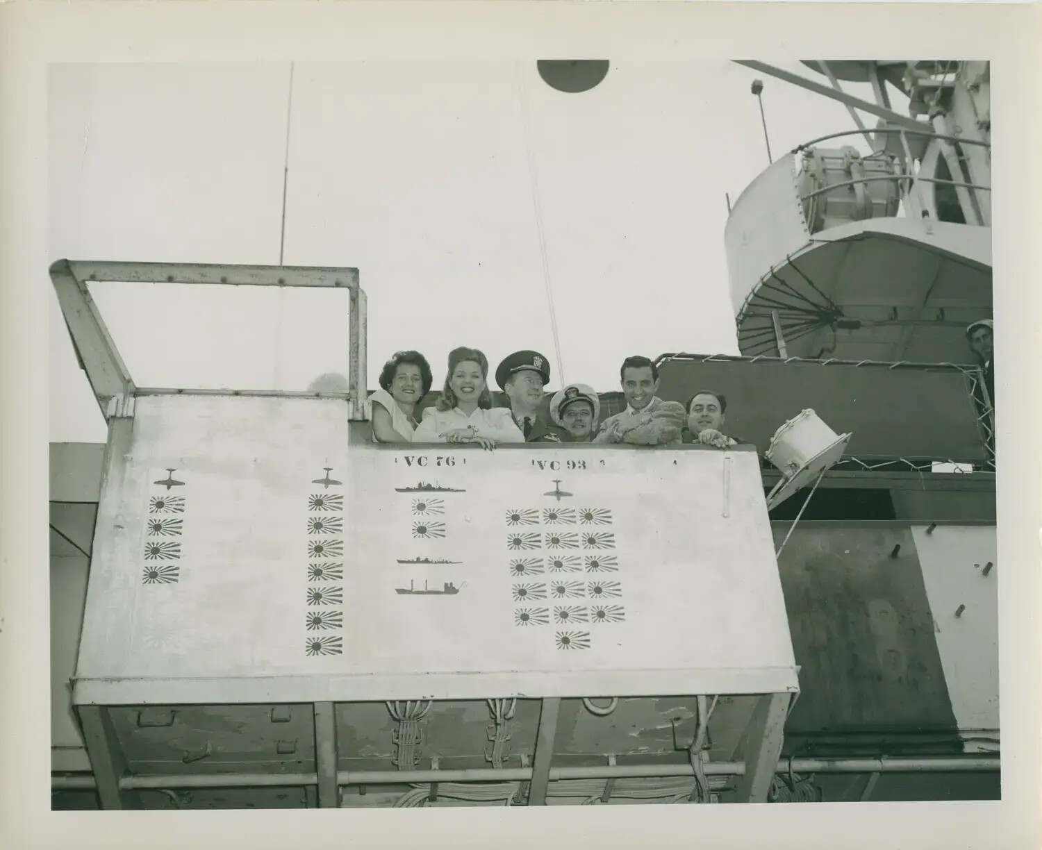 Visitors Pose by the Combat Scoreboard Aboard USS Petrof Bay (CVE-80), Crediting VC-76 and VC-93