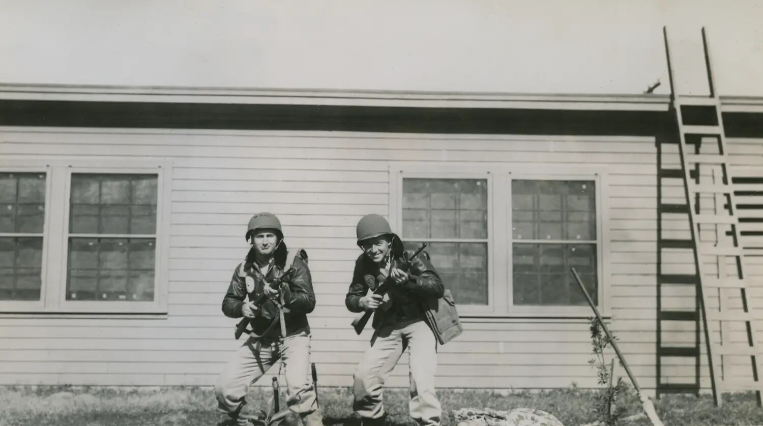 Two Servicemen Posing with Thompson Submachine Guns at Training Barracks, WWII Era