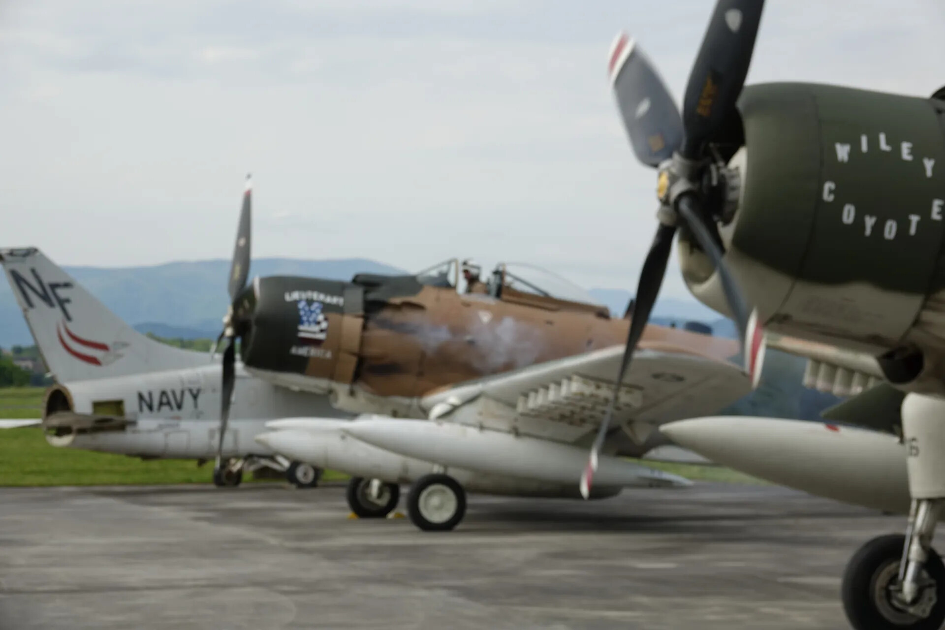 Multiple Warbirds on Ramp: A-1 Skyraiders 'Wiley Coyote' and 'Lieutenant America' with Navy Jet Trainer