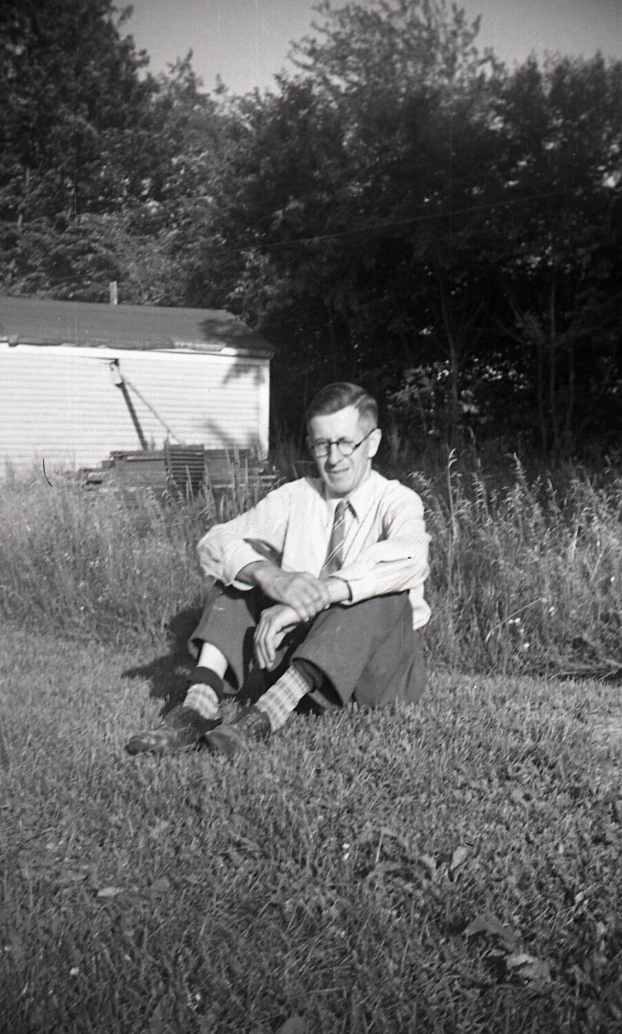Man Seated in Tall Grass Near a Garden Shed, c. 1940s