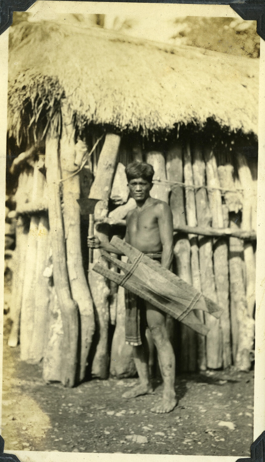 Man with Carved Wooden Shield Before a Traditional Dwelling, Manila Photo Album