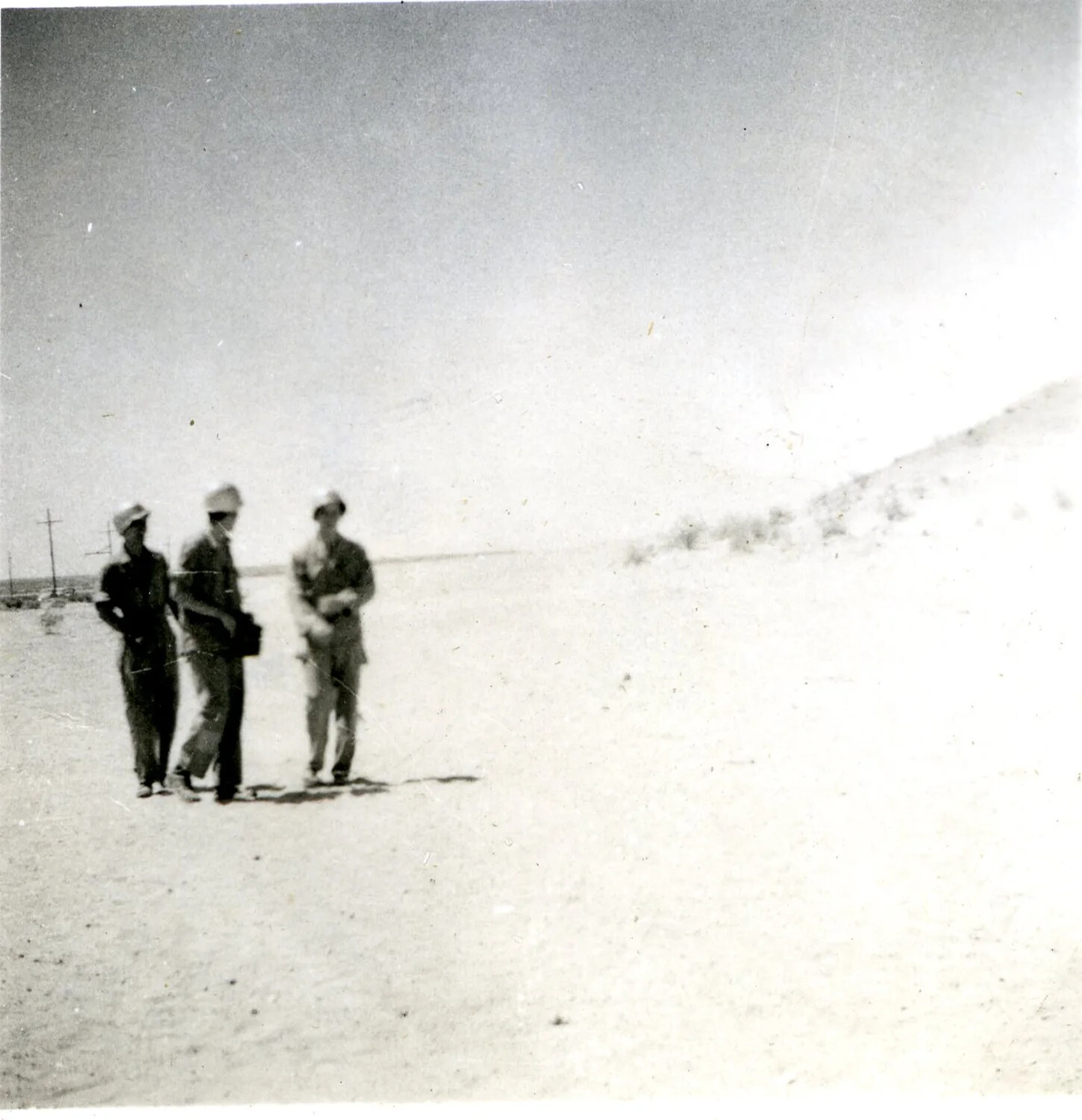Three Servicemen Walking Across an Open Desert Landscape