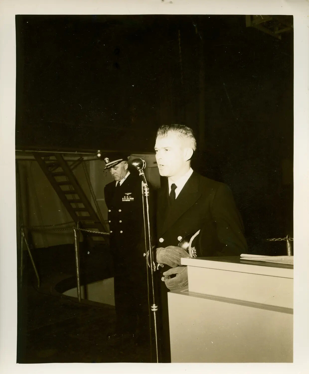 Civilian Speaker Addressing Ceremony Aboard Escort Carrier, with Naval Aviator Officer in Attendance