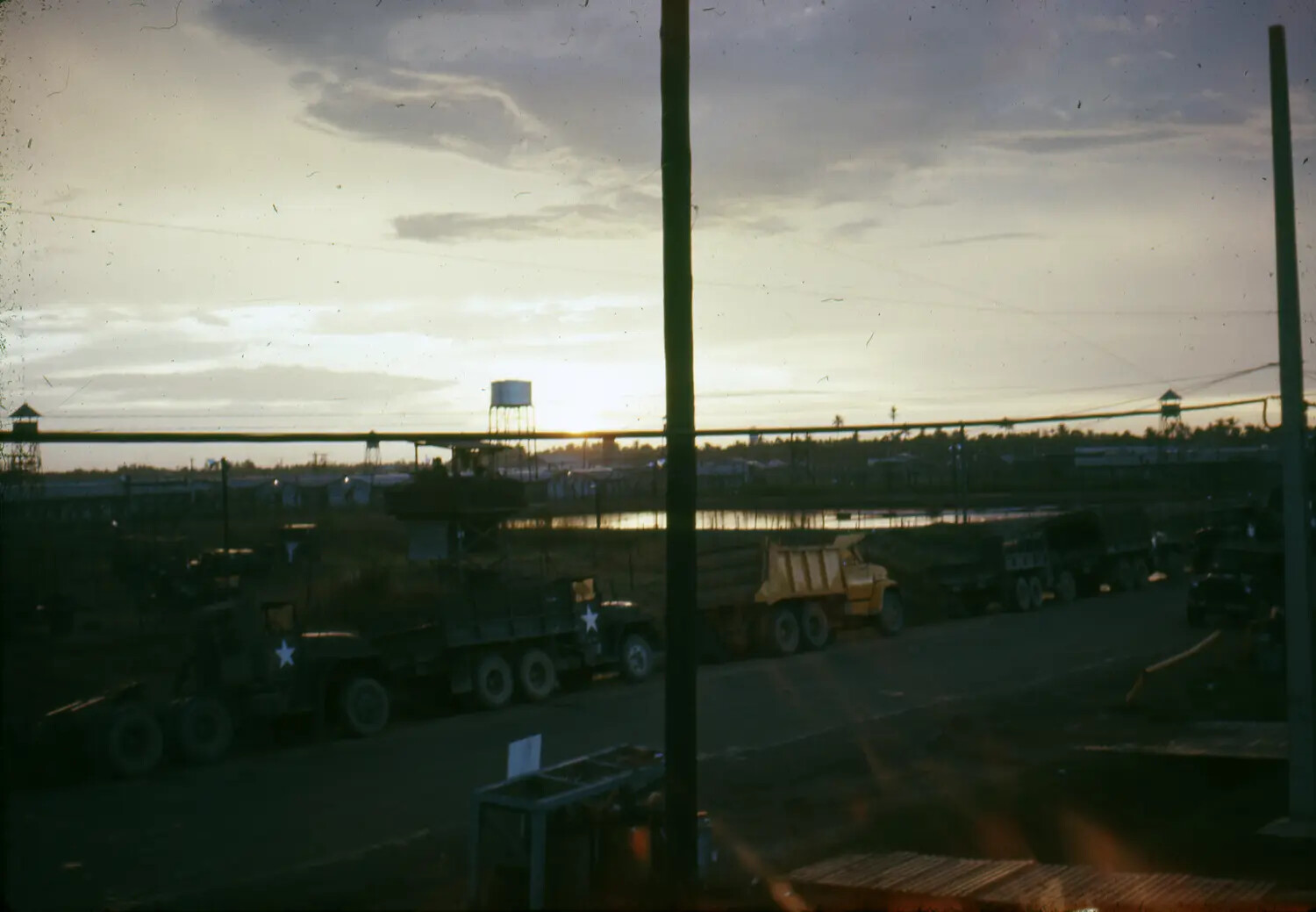 U.S. Military Base at Dusk — Trucks, Guard Towers, and Water Tower, Vietnam