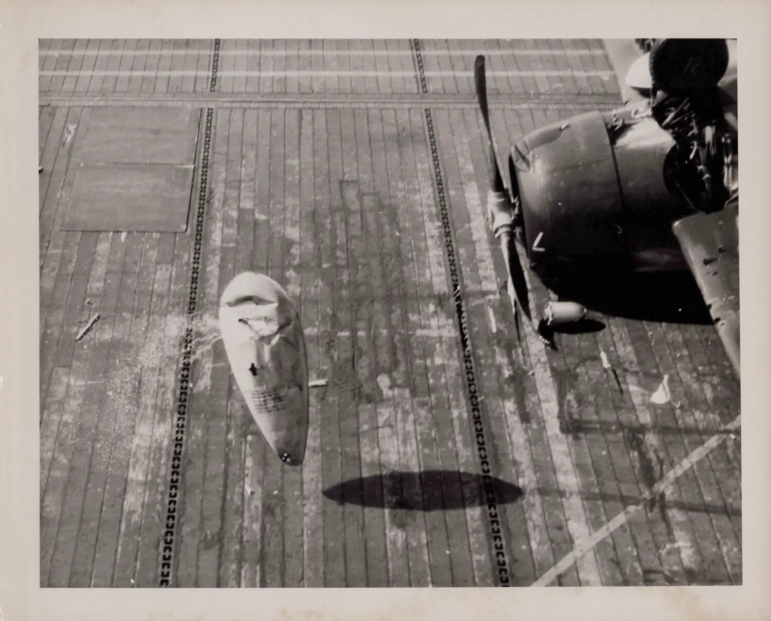 Detached Fuel Tank Beside Parked Aircraft on Escort Carrier Flight Deck, WWII