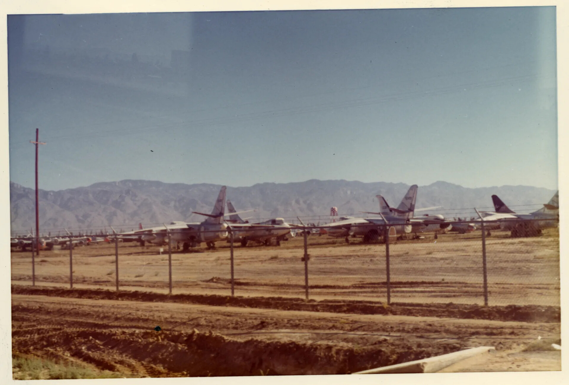 Rows of Stored Military Aircraft Behind Perimeter Fence, Desert Storage Facility
