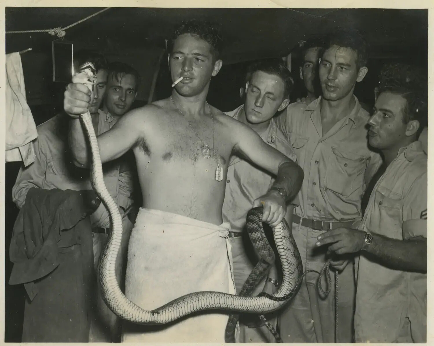 Airmen Gather Around Comrade Holding a Captured Snake, Pacific Theater Barracks