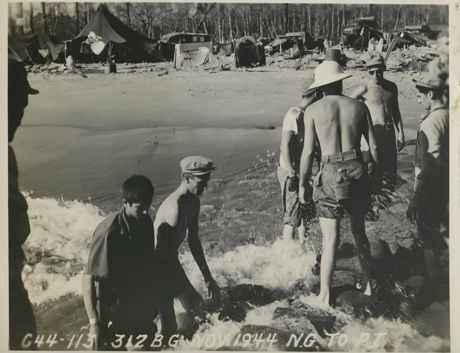 Servicemen Bathing in Surf Near War-Damaged Encampment, 312th Bombardment Group, November 1944