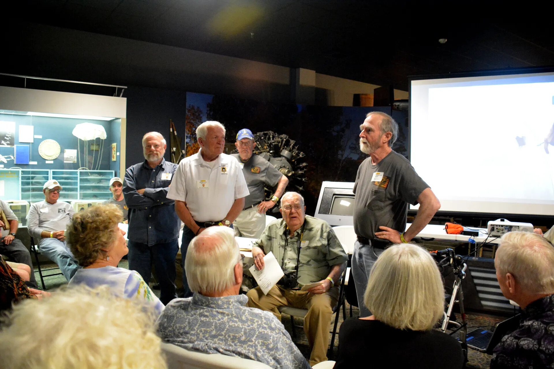 Veterans' Reunion Meeting, Aviation Museum — Small Group Gathered Around Seated Elder Veteran