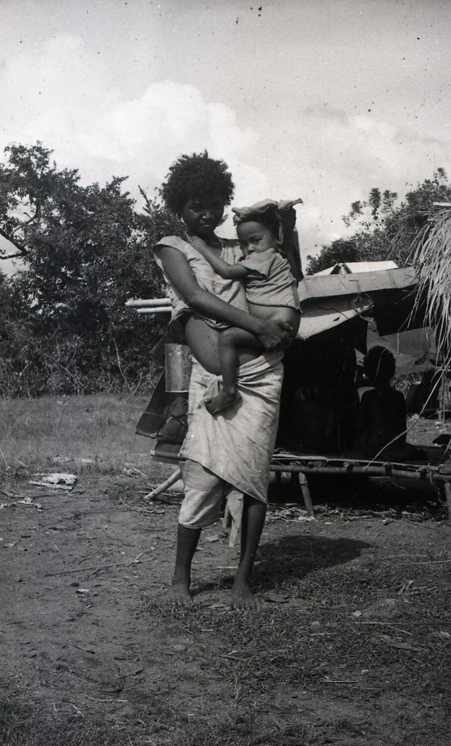 Woman Holding Child Beside Improvised Shelter, Luzon, Philippines, World War II