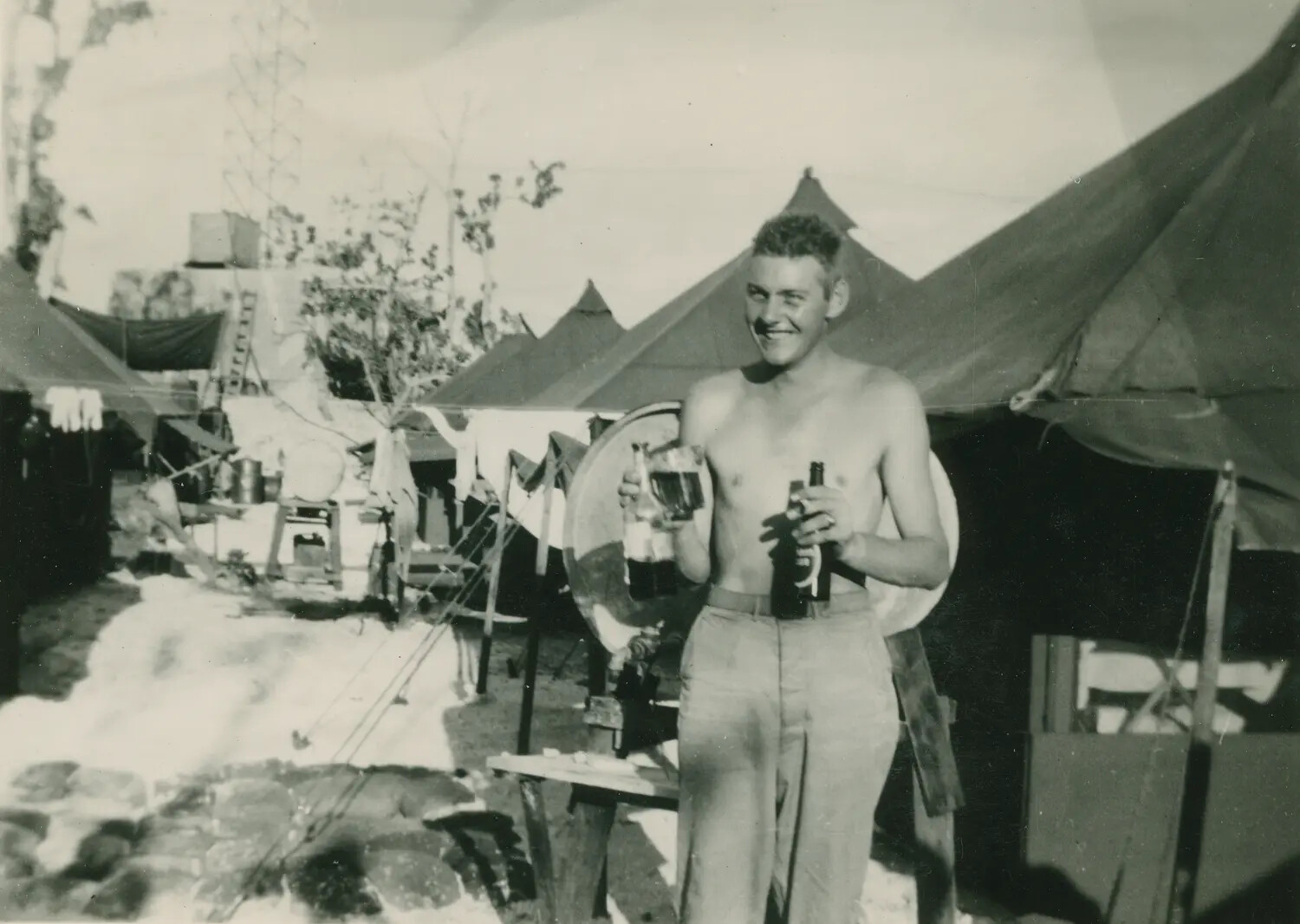 Shirtless Serviceman Holding Bottles in Tent Camp, WWII (McAleer Collection)