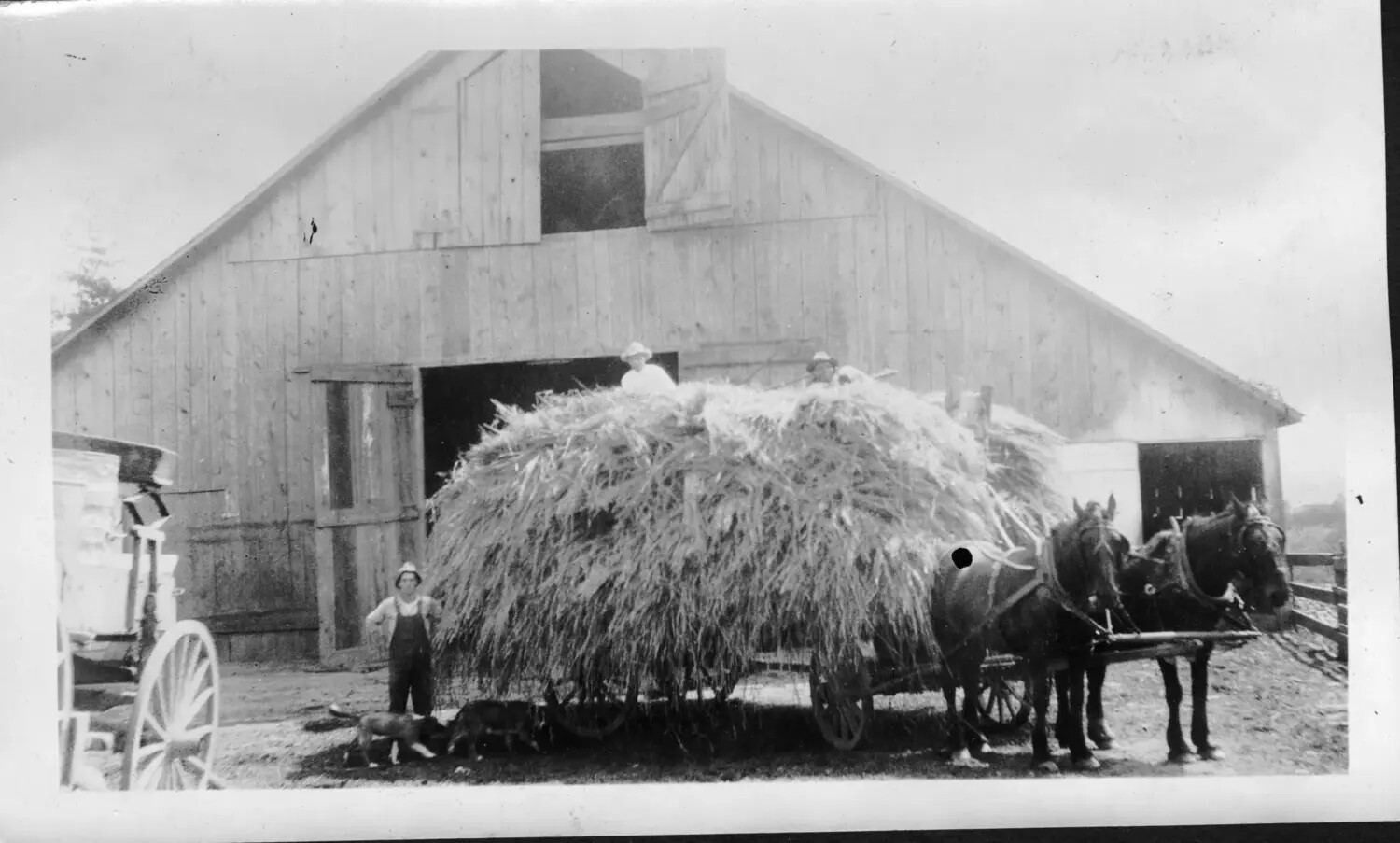 Farmhands and Loaded Hay Wagon Before a Large Barn