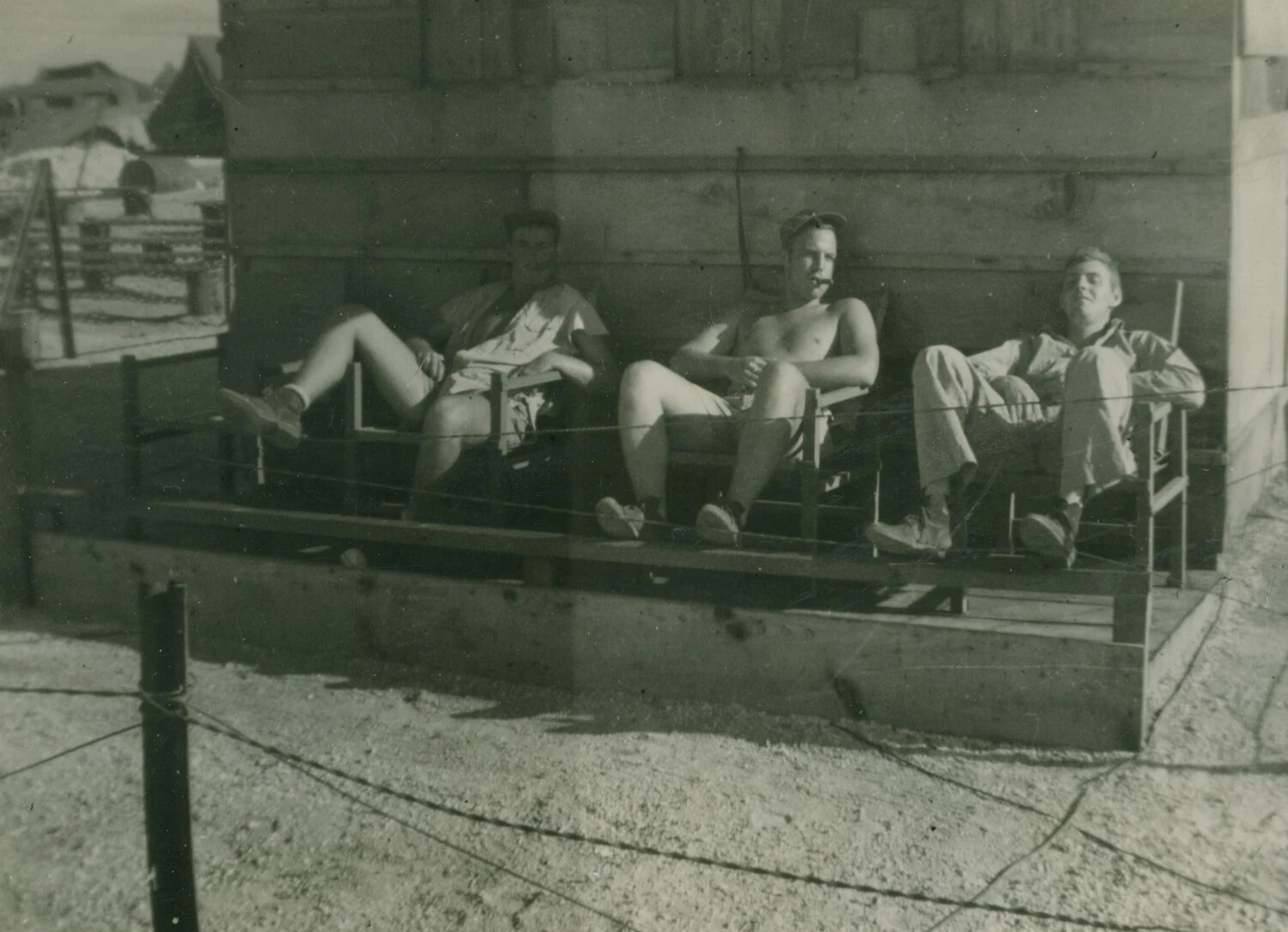 Three Servicemen Relaxing on Wooden Platform, Snow-Dusted Base Setting