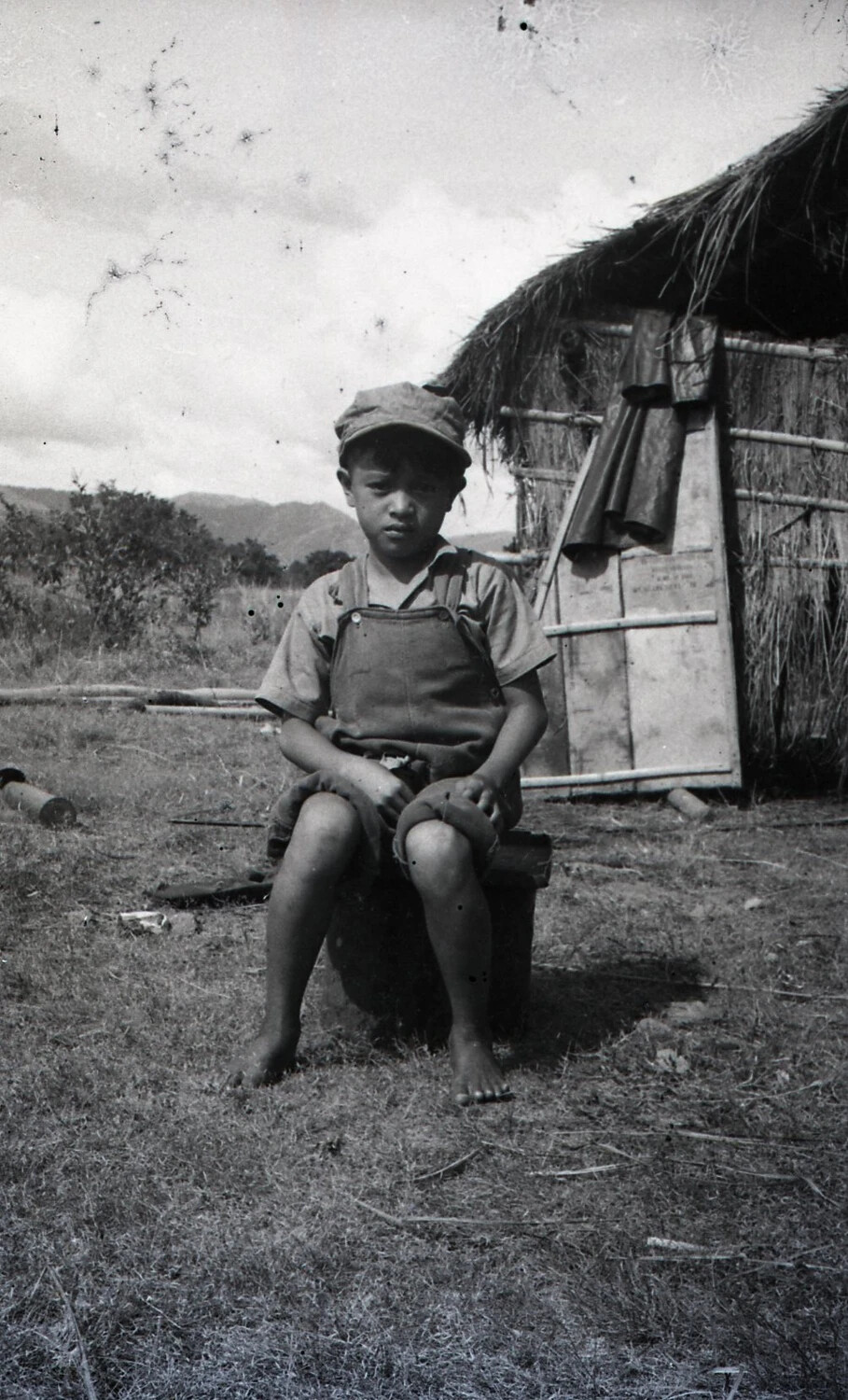 Filipino Boy Seated Before a Nipa Hut, Luzon, Philippines, WWII Era