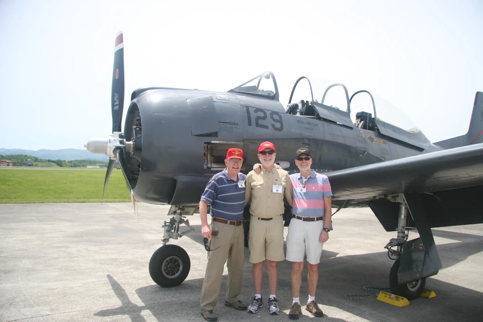 Three Reunion Attendees Pose Before T-28 "129 / Neal Melton" at the Tennessee Museum of Aviation