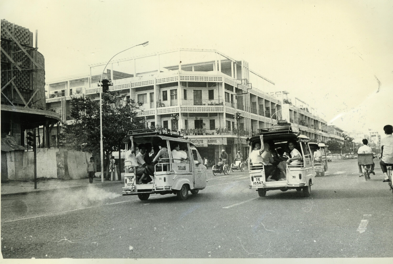 Shared 'Taxi-Bus' Vehicles No. 30 on Phnom Penh Street with Building Under Construction, Cambodia, c. late 1960s-early 1970s