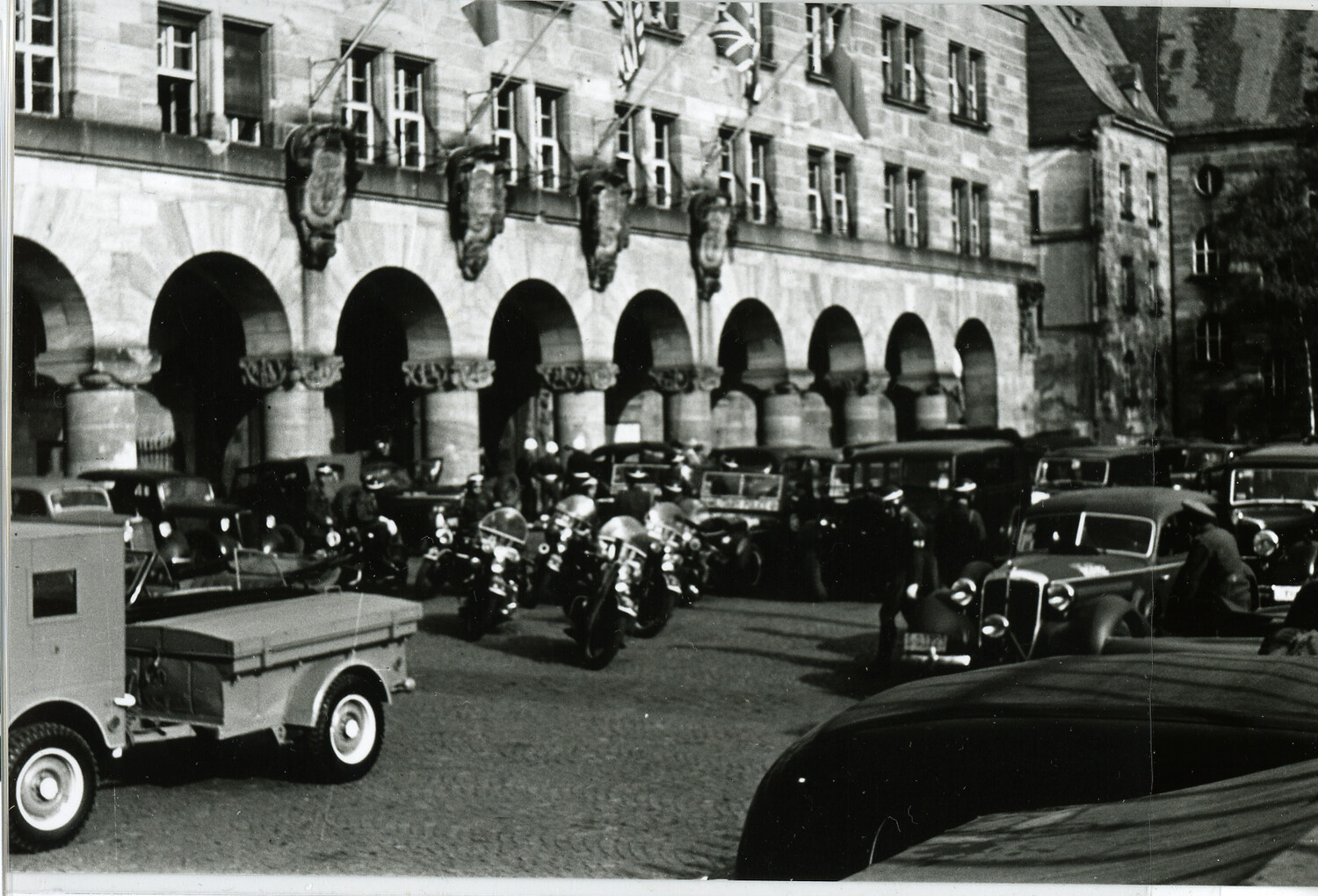 Vehicles and Motorcycles Parked Outside a Historic Arcaded Building, Nuremberg, Germany, Possibly Nuremberg Trials Era