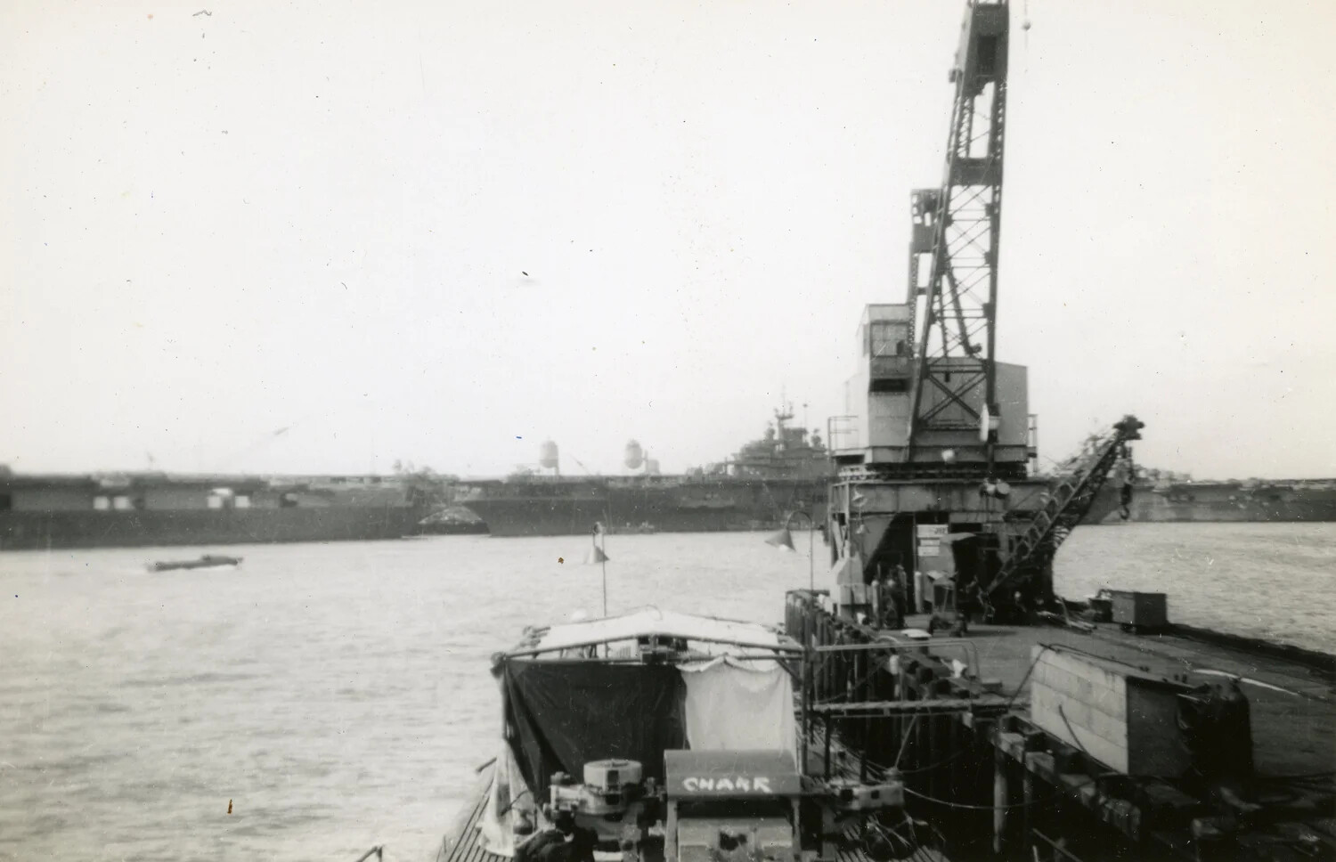 USS Charr (SS-328) Moored at a Pacific Fleet Base with Shoreside Crane and Capital Ship in Background, WWII