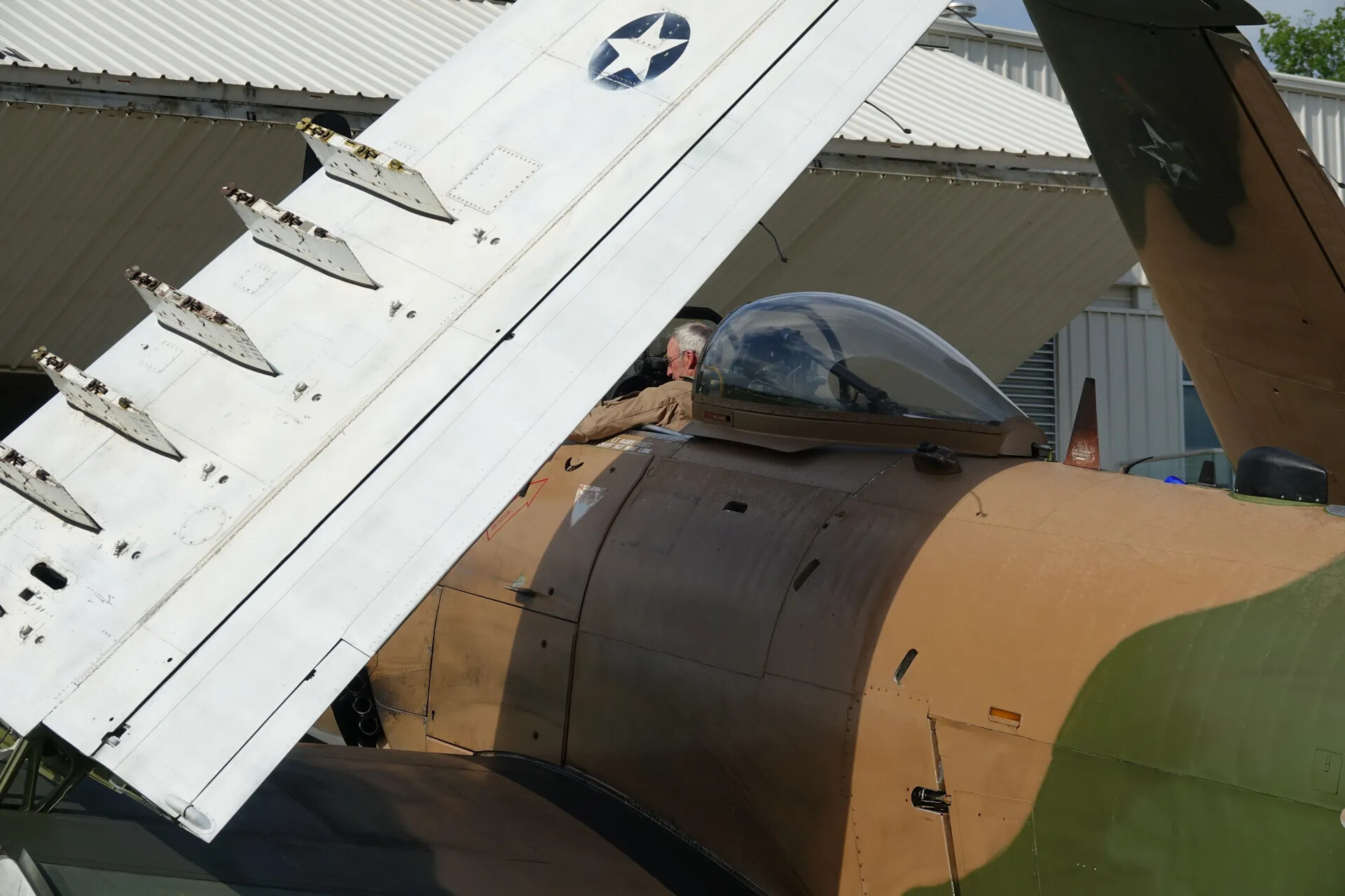 Man in Flight Suit Seated in A-1 Skyraider Cockpit, Wing Folded