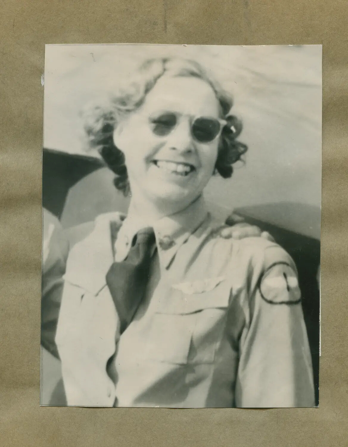 Portrait of Smiling Woman in Aviation Shirt with Pilot Wings, Seated Near Aircraft