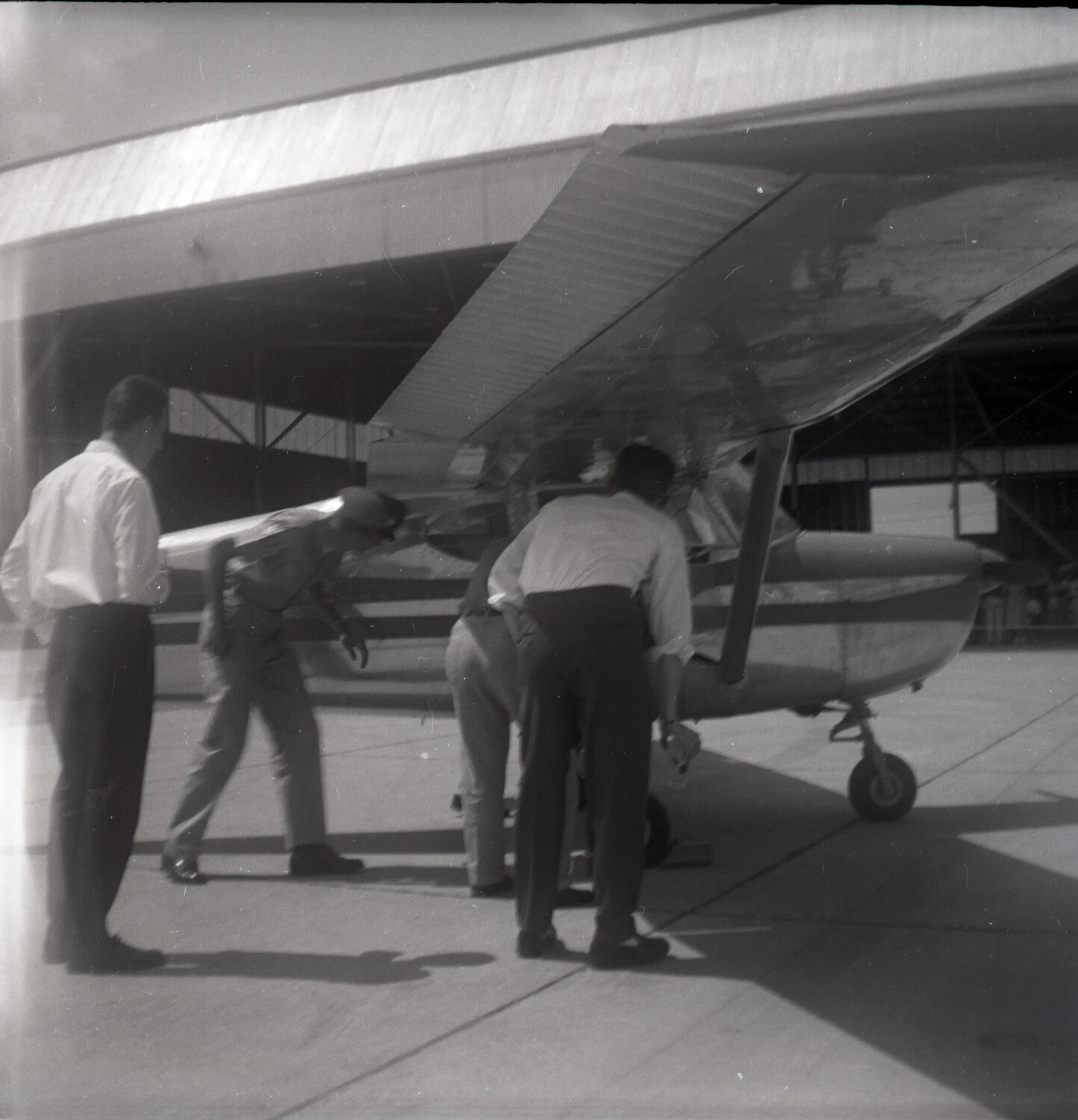 Ground Crew Inspecting a Light Aircraft Outside an Open Hangar