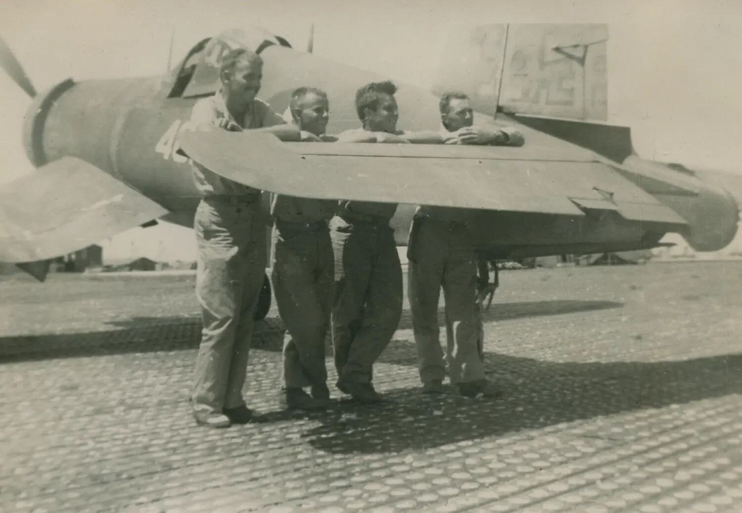 Four Servicemen Posing on the Wing of a Captured German Fighter Aircraft (Possible Focke-Wulf Fw 190), Airfield with Marston Matting