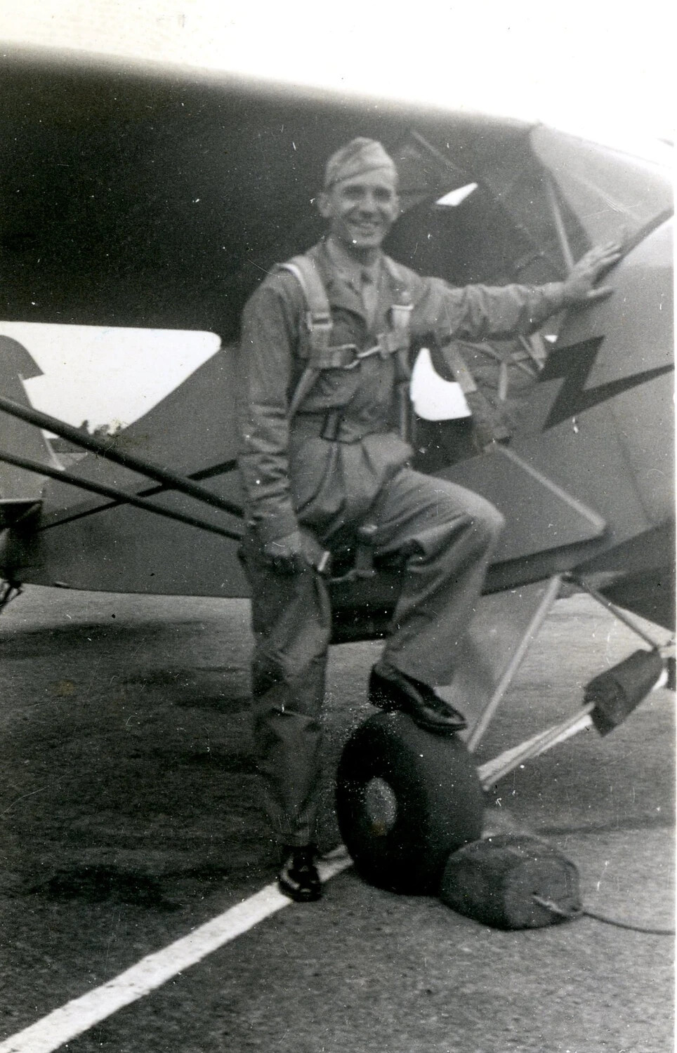 Airman Posing with Light Liaison Aircraft Bearing Lightning Bolt Nose Art