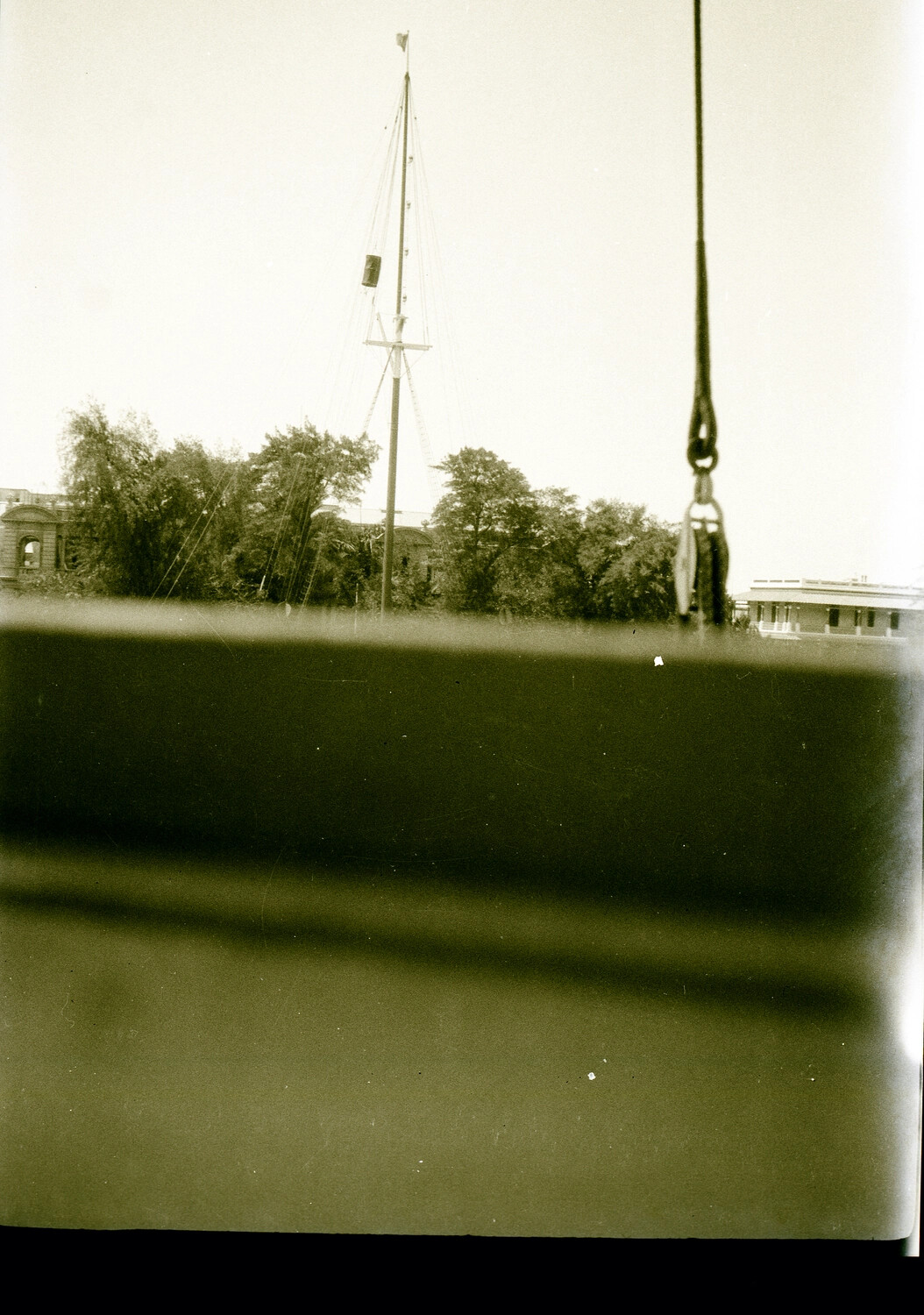 Shipboard View of Chinese Port with Mast, Cargo Hook, and Colonial Buildings, 1930s