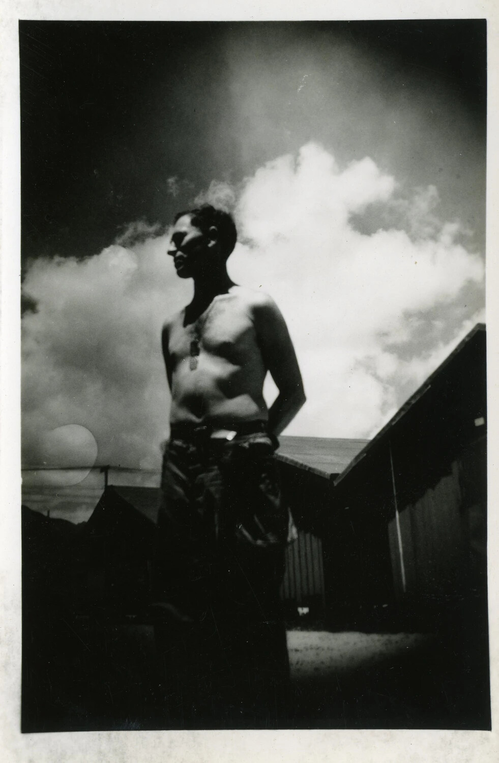 Silhouetted Portrait of Shirtless Serviceman with Dog Tags Against Cloudy Sky, World War II Era