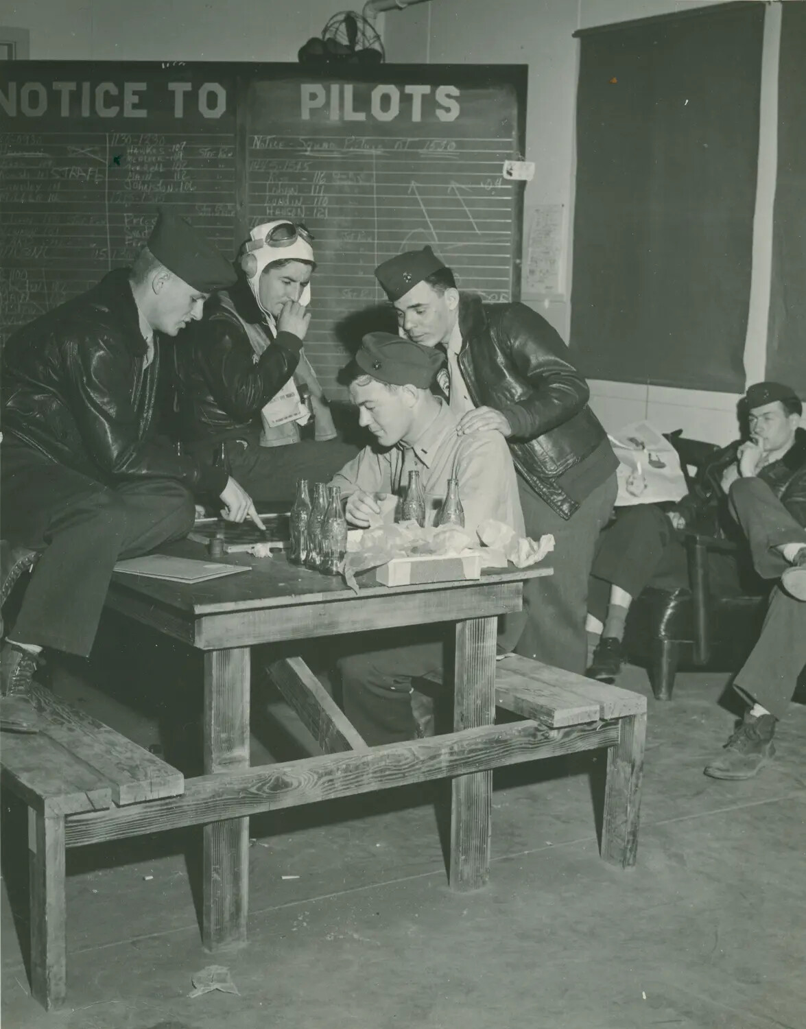 Pilots Playing Board Game in Squadron Ready Room Beneath 'Notice to Pilots' Chalkboard — McAleer Album