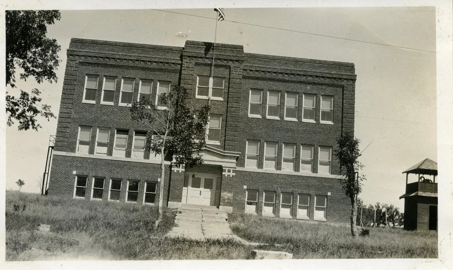Three-Story Brick Institutional Building with Central Entrance and Flagpole, Early Twentieth Century