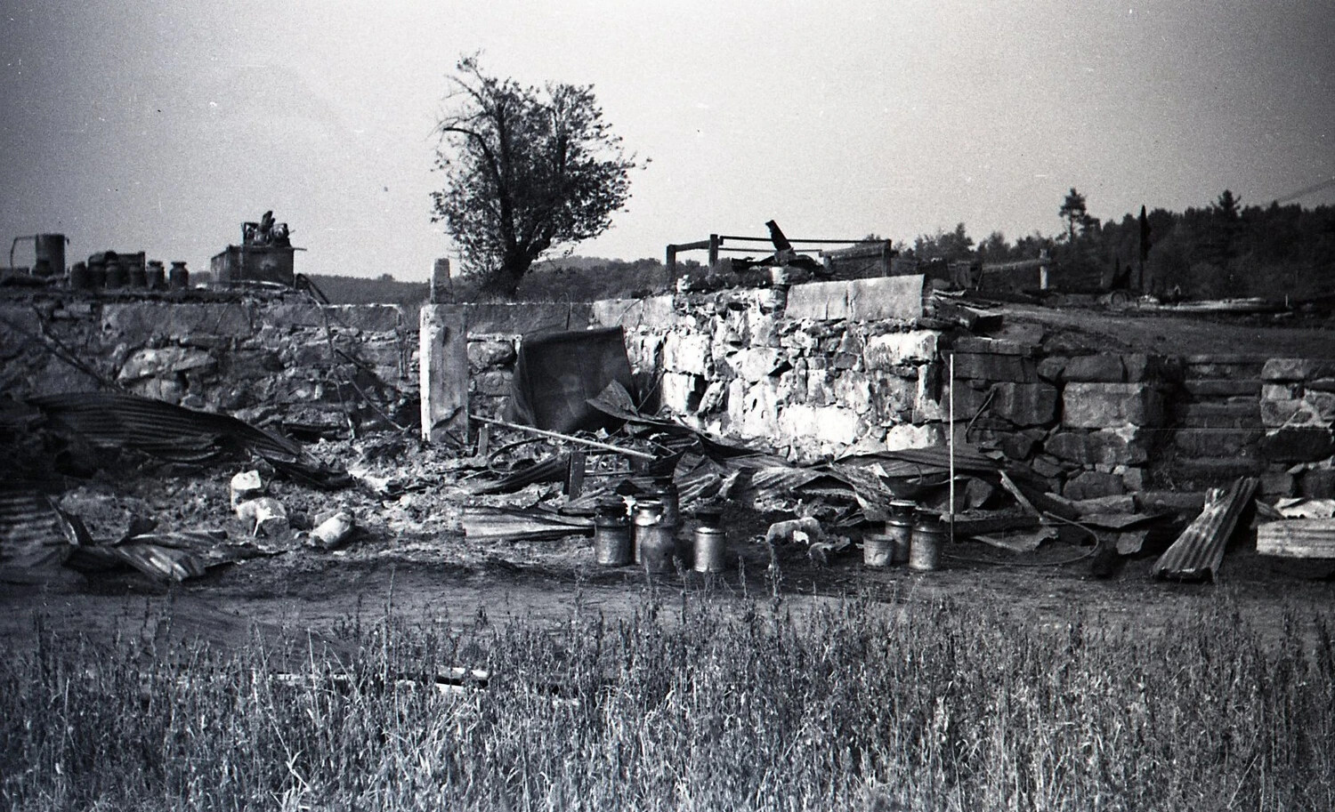 Wide View of Dairy Farm Fire Site with Milk Cans and Debris Field