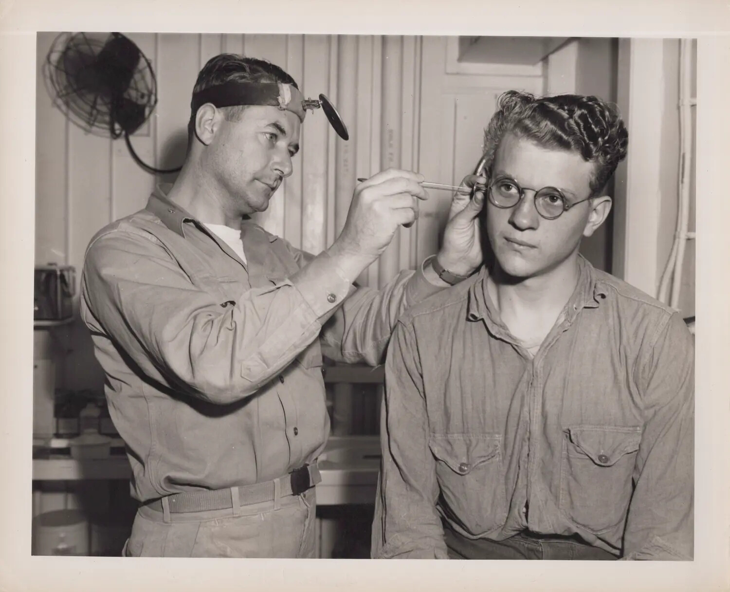 Navy Medical Officer Conducting Ear Examination Aboard Ship, WWII