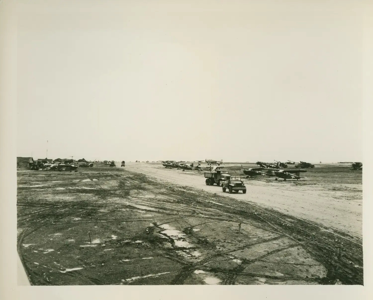 Forward Airstrip with Liaison Aircraft and Vehicles, Pacific Theater, WWII (USS Petrof Bay Collection)