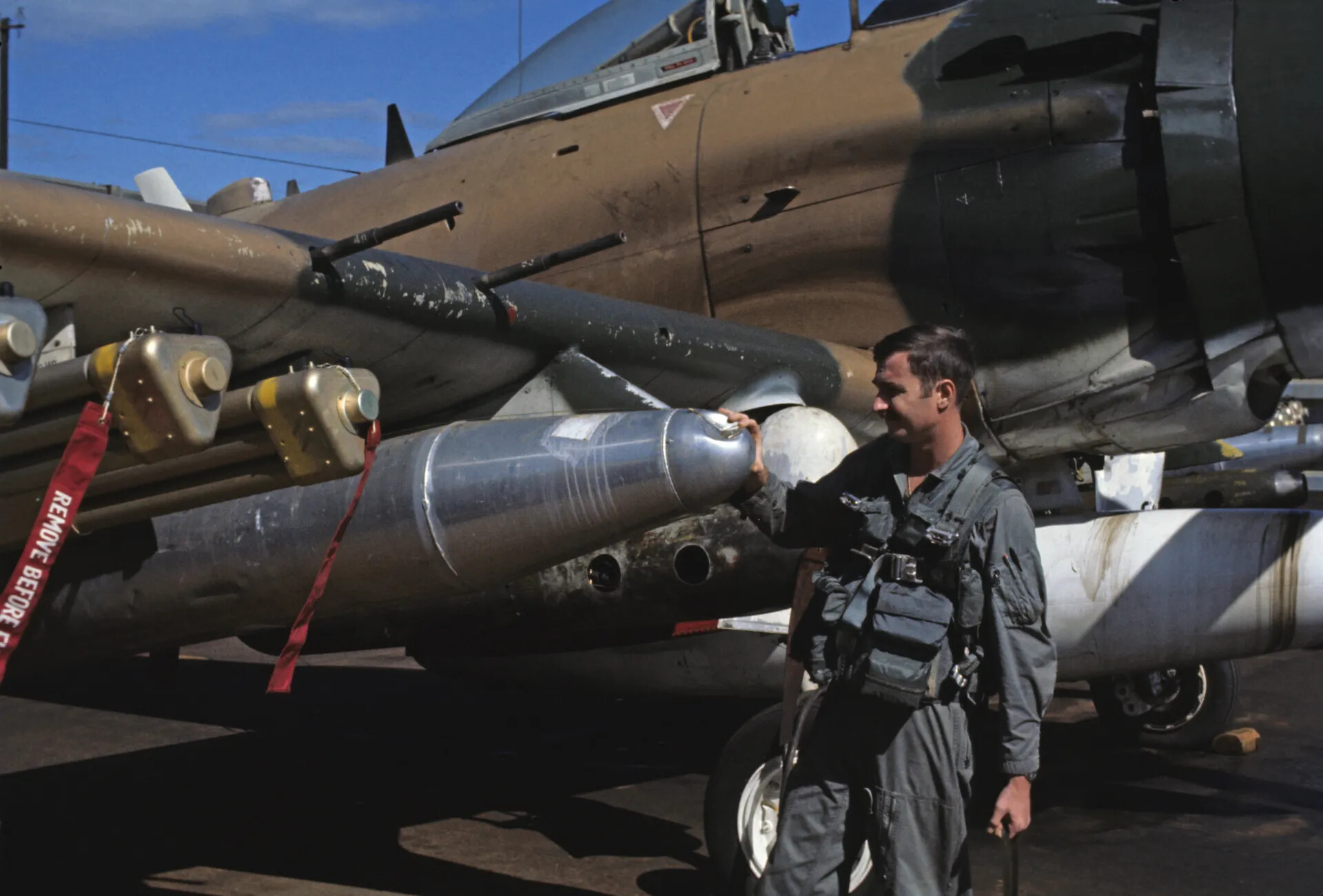 Pilot Inspecting Ordnance Beside A-1 Skyraider on Flight Line