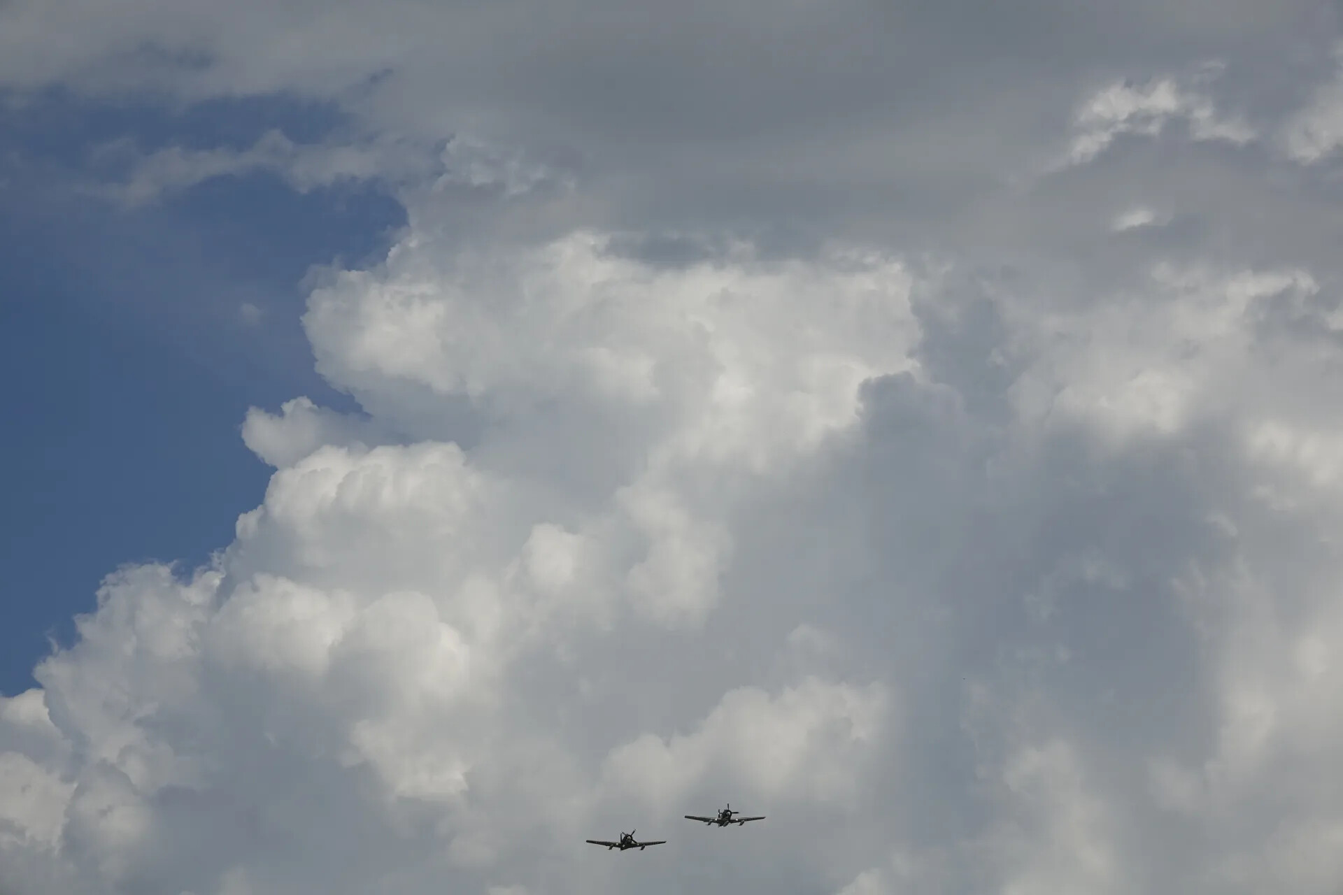 Two A-1 Skyraiders in Formation Flight Against Cumulus Clouds