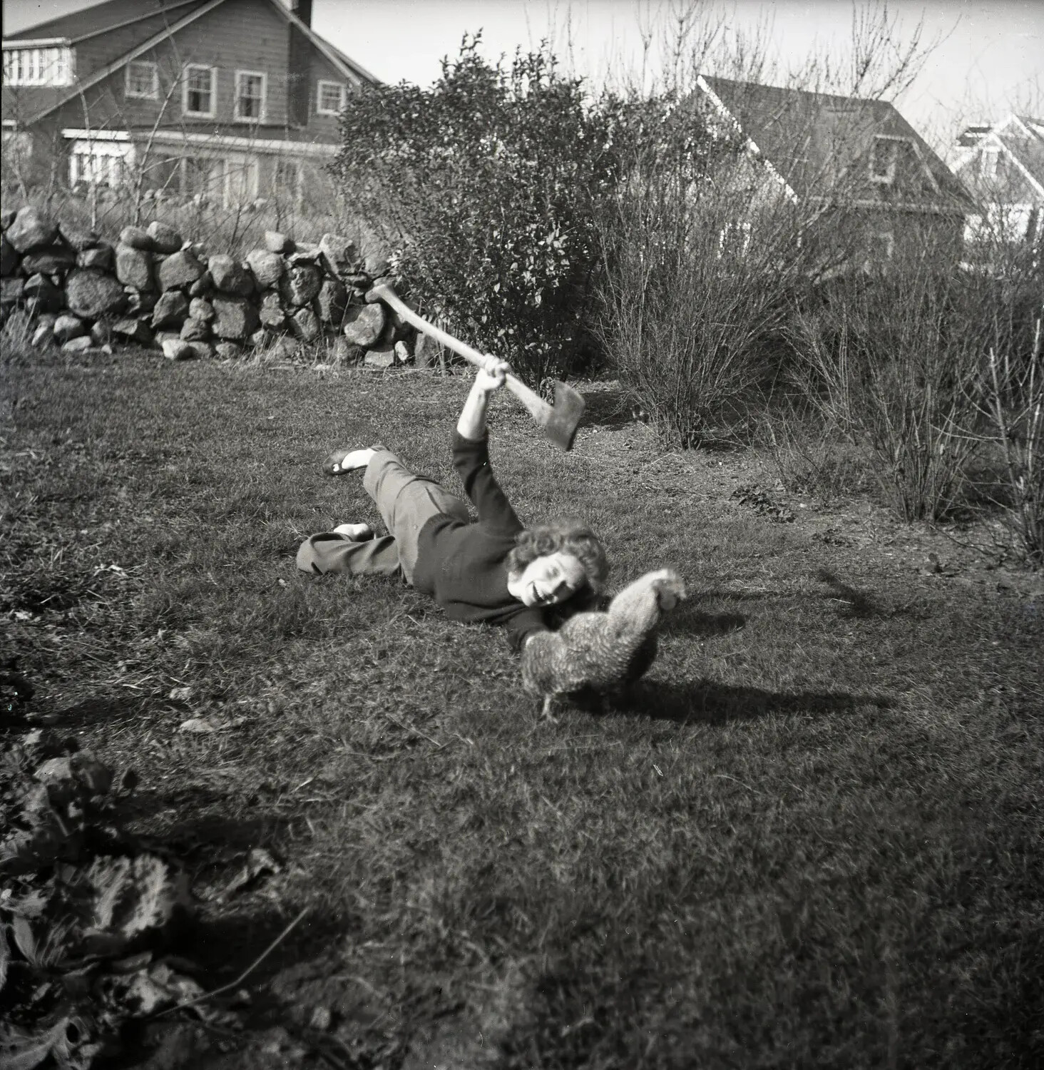 Candid Snapshot of a Woman Posing Playfully with a Hatchet and Chicken in a Backyard (Misfiled Item)